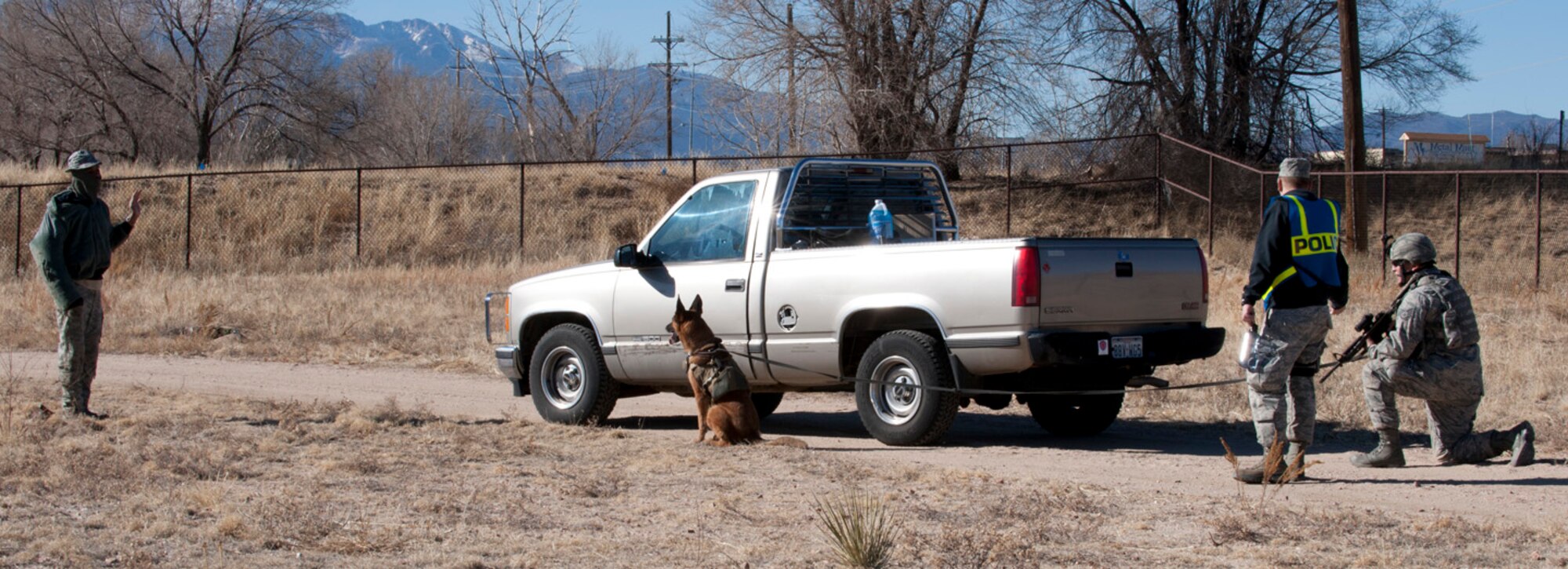 Staff Sgt. Rafael Valdez, a handler with the 21st Security Forces Squadron Military Working Dog Section, under the guidance of Tech. Sgt Loren Surley, 21st SFS MWD trainer, confronts an insurgent during a training exercise for teams of K9 handlers and their dogs at Peterson Air Force Base. The intent of this training was to familiarize the K9 teams with 'outside-the-wire' missions while deployed. Training like this is imperative for both handlers and dogs since they are often responsible for team safety during deployed missions. (U.S. Air Force photo/Staff Sgt. J. Aaron Breeden) 