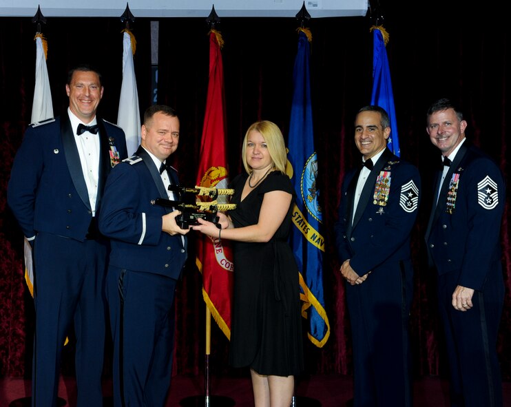 Monica Anderson, spouse of U.S. Air Force Master Sgt. Jason Anderson, 18th Aircraft Maintenance Squadron, accepts an award on behalf of her husband from Col. Brian McDaniel, 18th Wing vice commander, during the annual awards ceremony at the Rocker NCO Club on Kadena Air Base, Japan, Feb. 9, 2013. Anderson was recognized as Team Kadena's First Sergeant of the Year for 2012. (U.S. Air Force photo/Airman 1st Class Justin Veazie)