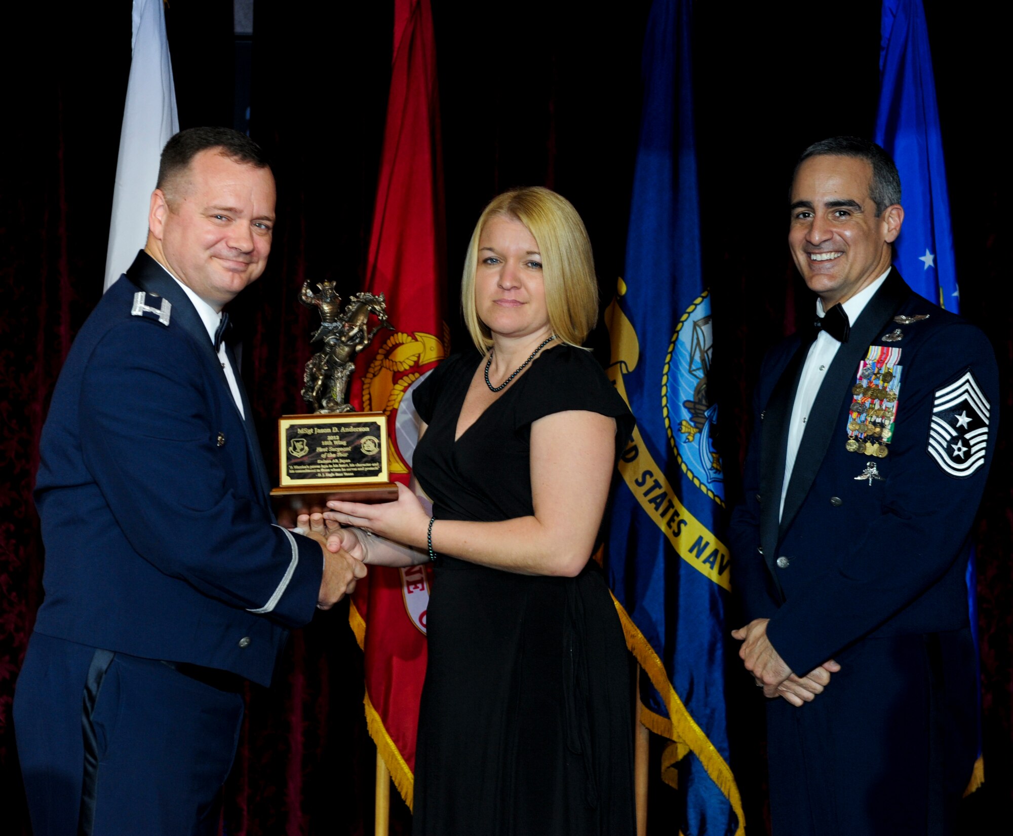 Monica Anderson, spouse of U.S. Air Force Master Sgt. Jason Anderson, 18th Aircraft Maintenance Squadron, accepts an award on behalf of her husband from Col. Brian McDaniel, 18th Wing vice commander, during the annual awards ceremony at the Rocker NCO Club on Kadena Air Base, Japan, Feb. 9, 2013. Anderson was recognized as the 18th Wing First Sergeant of the Year for 2012. (U.S. Air Force photo/Airman 1st Class Justin Veazie)
