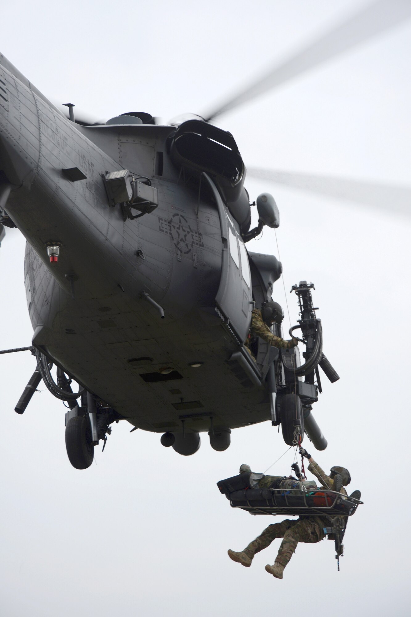 A pararescueman from the 31st Rescue Squadron is raised into a 33rd Rescue Squadron Pave Hawk along with his mock patient during a combat rescue exercise scenario of a simulated downed aircraft during a war week exercise at Marine Corps Camp Hansen's Combat Town, Japan, Feb. 7, 2013. War week was a three-day battery of combat and rescue scenarios to train members of the 31st and 33rd Rescue squadrons before an upcoming deployment. (U.S. Air Force Photo/Tech. Sgt. Jocelyn L. Rich-Pendracki)