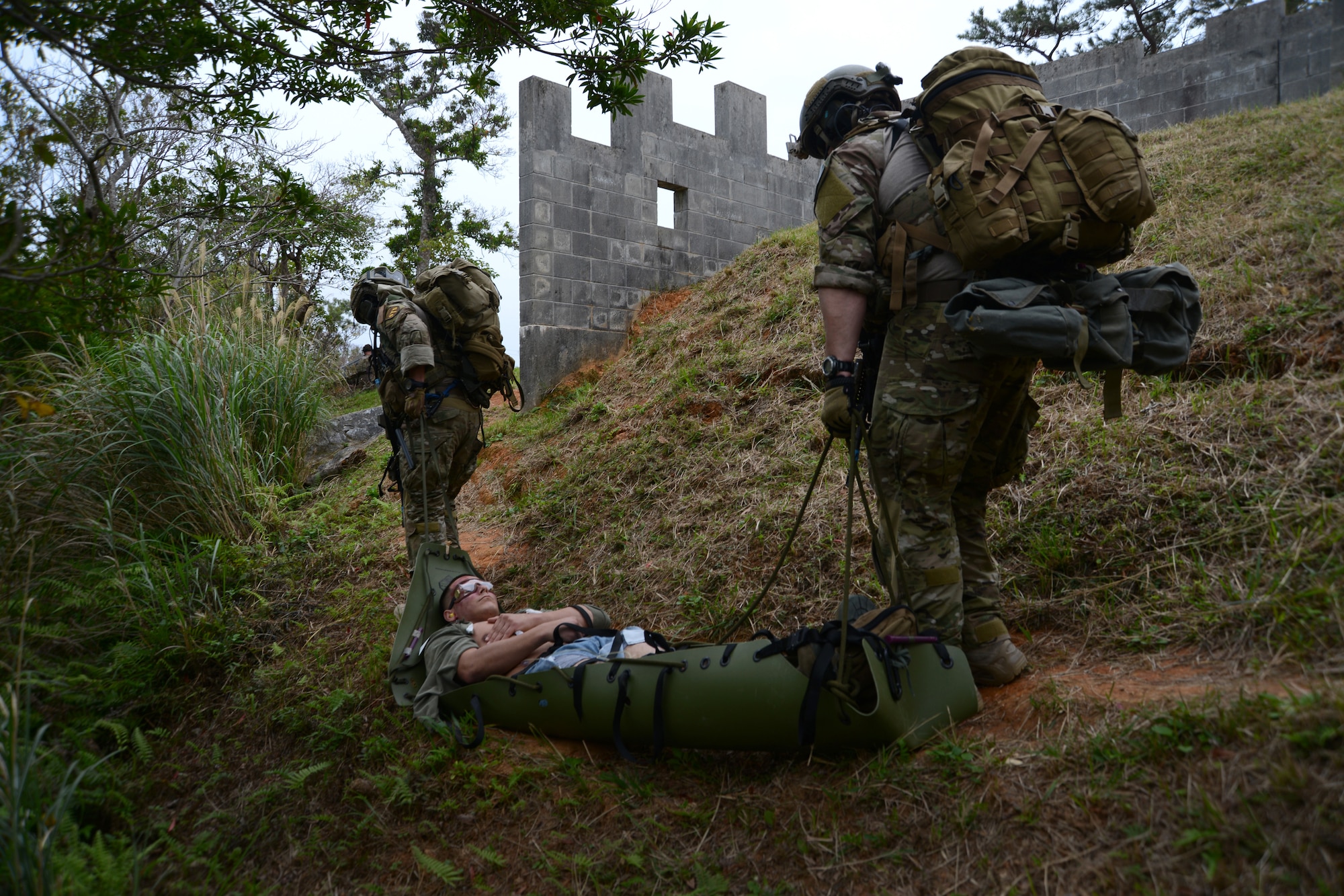 U.S. Air Force Airman 1st Class Torrey Sanchez, 18th Component Maintenance Squadron aerospace propulsion journeyman, acting as an injured crewmember from a simulated helicopter crash is transported to safety by pararescuemen Staff Sgt. Elmer Quijada and Staff Sgt. Jacob Schaumberg the 31st Rescue Squadron pararescuemen, during a war week exercise at Camp Hansen's Combat Town, Japan, Feb. 7, 2013. Quijada is a traditional guardsman from the 123rd Special Tactics Squadron, Kentucky Air National Guard. He is here training with the team that he will be deploying with. (U.S. Air Force Photo/Tech. Sgt. Jocelyn L. Rich-Pendracki)