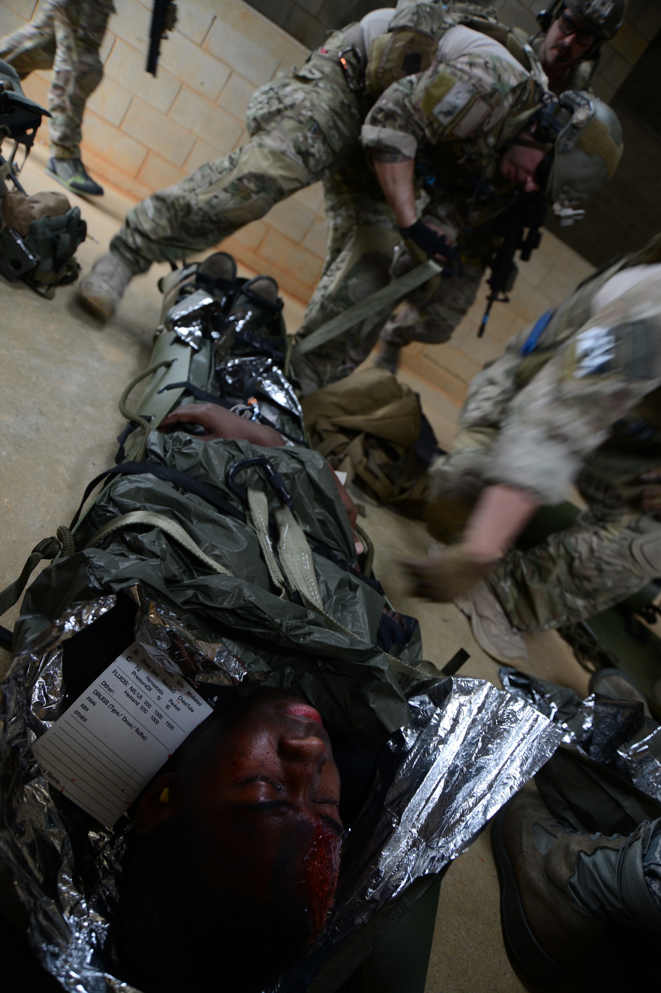 U.S. Air Force Airman 1st Class Leonard Hutchenson, 18th Maintenance Squadron knowledge operator acting as an injured aircrew member, is secured for transport by a Staff Sgt. Jacob Schaumberg the 31st Rescue Squadron pararescueman, while other members of his team provide security, during a war week exercise at Marine Corps Camp Hansen's Combat Town, Japan, Feb. 7, 2013. War week was a three-day battery of combat and rescue scenarios to train members of the 31st and 33rd Rescue squadrons before an upcoming deployment. (U.S. Air Force Photo/Tech. Sgt. Jocelyn L. Rich-Pendracki)