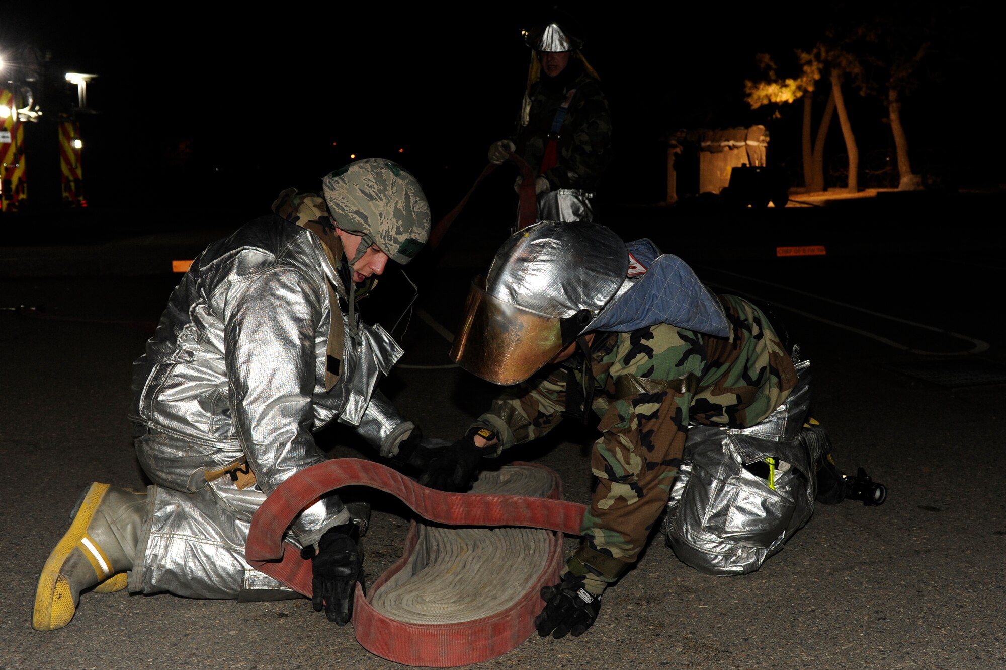 KUNSAN AIR BASE, Republic of Korea --  Airman 1st Class Alec Ribbink, left, and Mr. Yi Son U, 8th Civil Engineer Squadron firefighters, wrap up a hose as Tech. Sgt. Michael Jackson, 8th CES firefighter, keeps tension on the slack during the early morning hours of exercise Beverly Bulldog 13-2 at Kunsan Air Base, Republic of Korea, Feb. 13, 2013. The scenario allowed the firefighters to practice their skills fighting fires and searching for injured members. (U.S. Air Force photo by Senior Airman Marcus Morris/Released) 