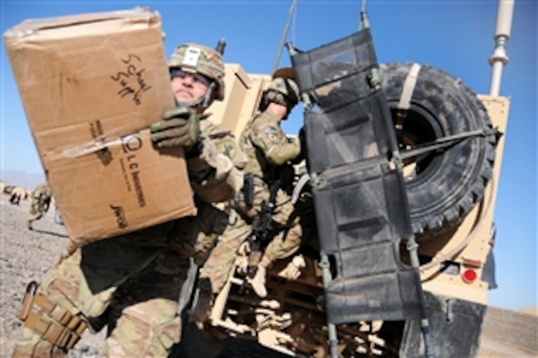 U.S. Army Lt. Col. Mark Martin, left, unloads a box of school supplies during a visit to a local returnee and refugee village in Farah province, Afghanistan, Feb. 9, 2013. Martin, a civil affairs officer, is assigned to Provincial Reconstruction Team Farah.