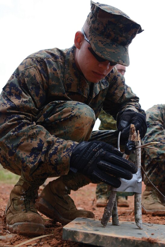 Cpl. Robert A. O'Connell places an improvised shaped charge on a piece of steel-plate armor Feb. 8 at Camp Schwab during basic demolition training. Sticks were used to isolate the effects of the shaped charge, providing a safe stand-off distance for when Marines detonate the charge. Oâ€™Connell is a combat engineer with 9th ESB, 3rd MLG, III MEF. Photo by Cpl. Mark W. Stroud