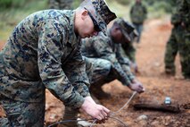 Lance Cpl. Adam A. Abbett uses a right-angle knot to attach a charge to a length of detonation cord Feb. 8 at Camp Schwab during basic demolition training. The training was hosted by Marines with 3rd Explosive Ordnance Disposal Company, 9th ESB, 3rd MLG, III MEF. Abbett is a motor vehicle mechanic with 9th ESB.  