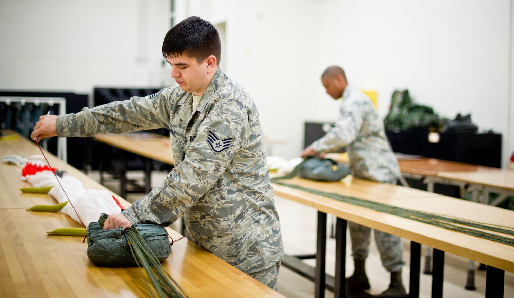 YOKOTA AIR BASE, Japan -- Staff Sgt. Bryan Vrabel, 374th Operations Support Squadron aircrew flight equipment journeyman, packs a parachute after making repairs at Yokota Air Base, Japan, Feb. 14, 2013. Over time, the fabric in the parachutes can break down, requiring periodic maintenance. (U.S. Air Force photo by Staff Sgt. Stacy Moless)