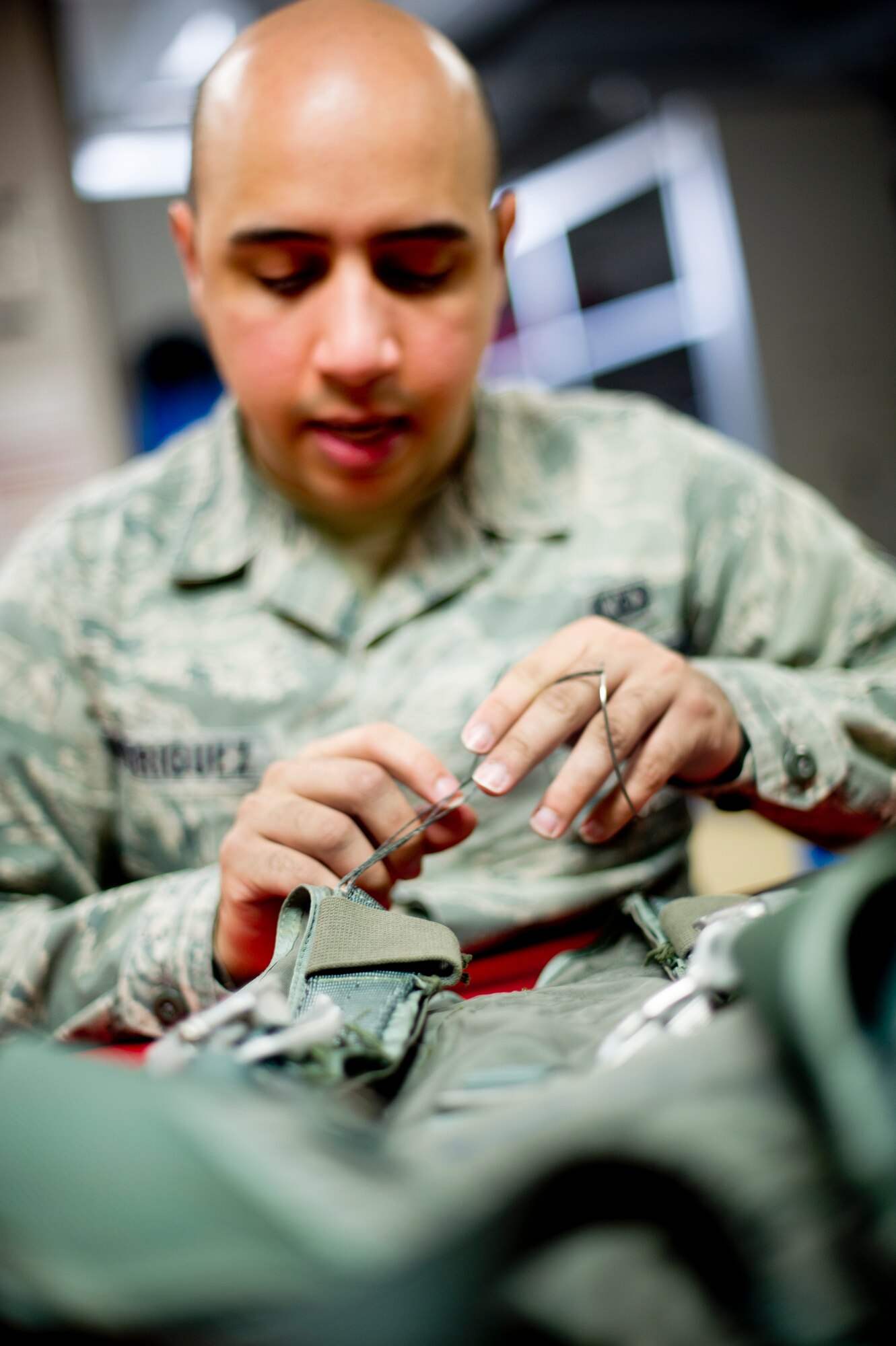 YOKOTA AIR BASE, Japan -- Senior Airman Phillip Rodriguez, 374th Operations Support Squadron aircrew flight equipment journeyman, inspects a harness at Yokota Air Base, Japan, Feb. 14, 2013. The harness is only one piece of life-saving survival equipment technicians are responsible for maintaining to keep aircrew safe. (U.S. Air Force photo by Staff Sgt. Stacy Moless)