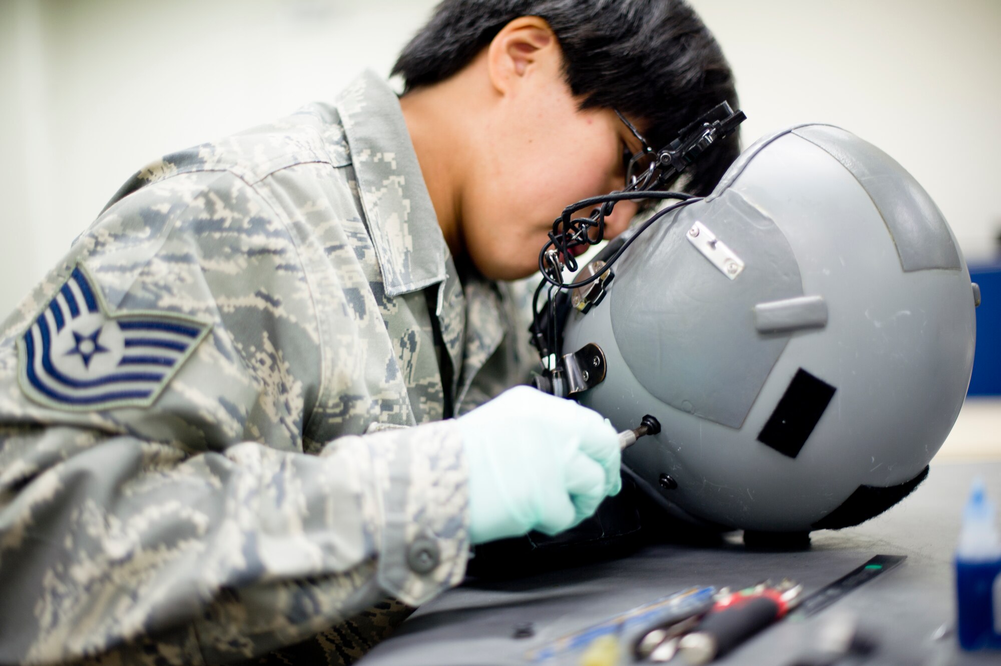 YOKOTA AIR BASE, Japan -- Tech. Sgt. Rhodelyn Merculio, 374th Operations Support Squadron aircrew flight equipment journeyman, reaches for a tool while inspecting a helmet at Yokota Air Base, Japan, Feb. 14, 2013.  Aircrew flight equipment technicians ensure life-saving survival equipment used by aircrew members is properly functioning by maintaining all the equipment with routine inspections. (U.S. Air Force photo by Staff Sgt. Stacy Moless) 