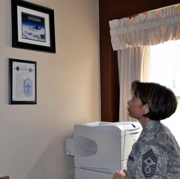 Command Chief Master Sgt. Ericka Kelly shown reminiscing about the events that made her the person she is today. The “Mission” photo, which is proudly displayed on her office wall, is a constant reminder of her devotion to duty, family and to the men and women of the 452d Air Mobility Wing Total Force. (U.S. Air Force photo by Staff Sgt. Joe Davidson)