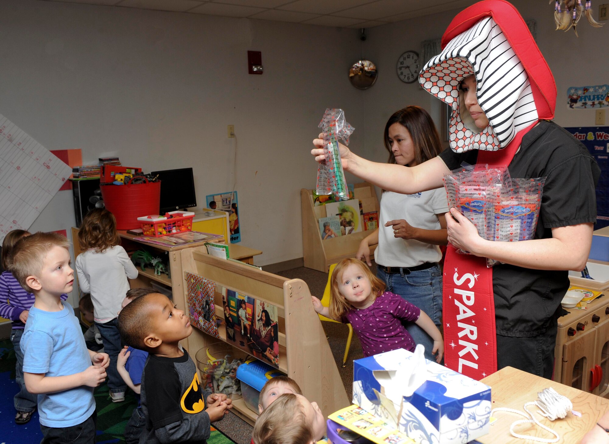 Staff Sgt. Taylor Johnson, 28th Medical Operations Squadron dental technician, dressed as Sparkle the Toothbrush, distributes teeth cleaning kits to the children at the Child Development Center on Ellsworth Air Force Base, S.D., Feb. 13, 2013. The dental hygiene kits contained a toothbrush, toothpaste, floss and information about how to keep teeth healthy and clean. (U.S. Air Force photo by Airman 1st Class Anania Tekurio/Released)