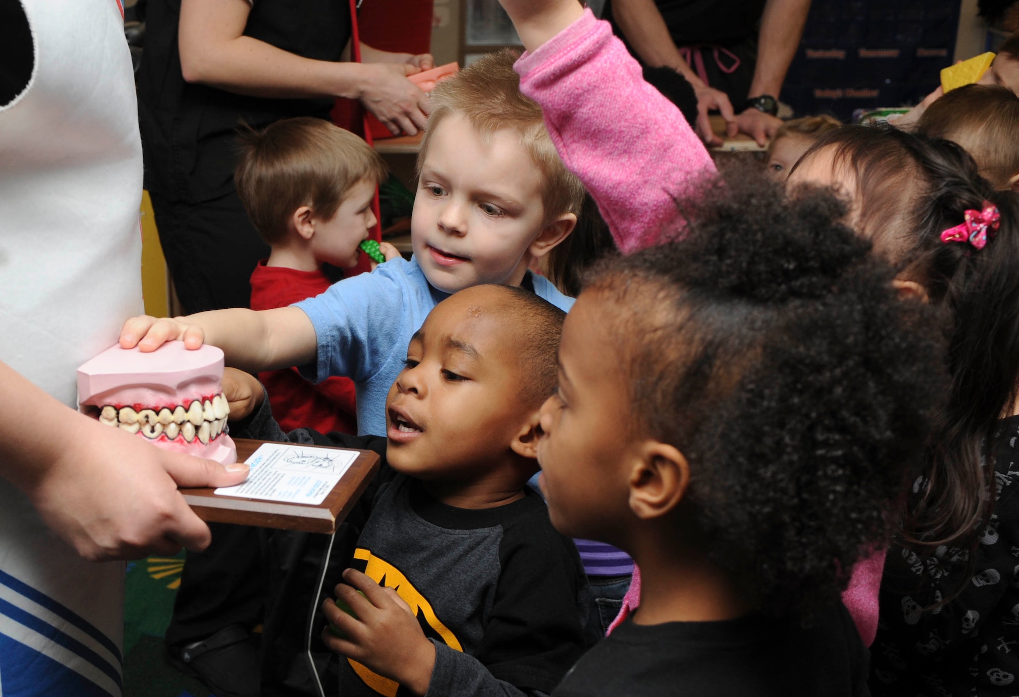 Four-year-old Marley Gilliam (center) and his fellow Child Development Center classmates examine a model of unhealthy teeth during the National Children’s Dental Health Month dental hygiene lesson put on by base dental professionals in the CDC at Ellsworth Air Force Base, S.D., Feb. 13, 2013. Staff used teeth displays to show the children what healthy and unhealthy teeth look like, and proper dental health care habits. (U.S. Air Force photo by Airman 1st Class Anania Tekurio/Released)  