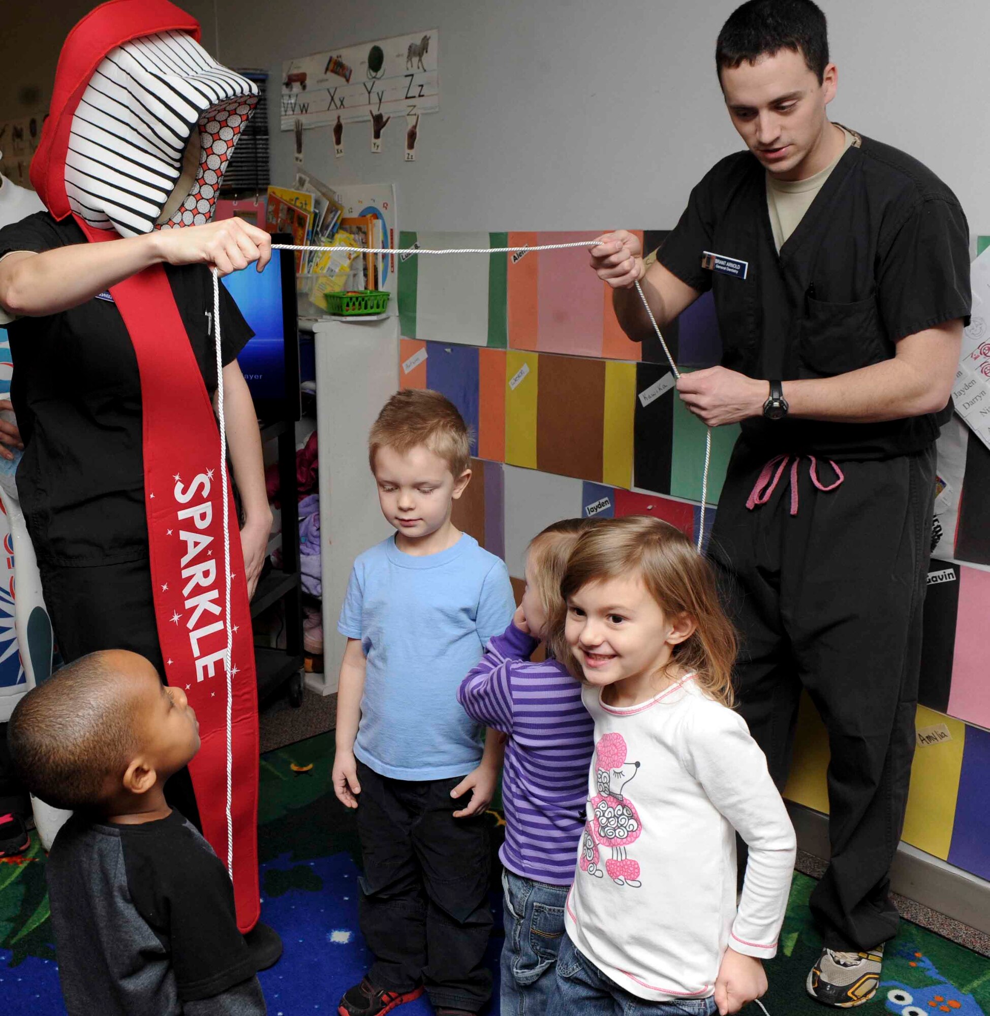 Capt. William Arnold, 28th Medical Operations Squadron dentist (right), and Staff Sgt. Taylor Johnson, 28th MDOS dental technician (left), dressed as Sparkle the Tooth Brush, demonstrate how to properly floss for children enrolled in the Child Development Center on Ellsworth Air Force Base, S.D., Feb. 13, 2013. The base dental staff visited several facilities on base to teach children the importance of proper dental care as part of National Children’s Dental Health Month. (U.S. Air Force photo by Airman 1st Class Anania Tekurio/Released) 