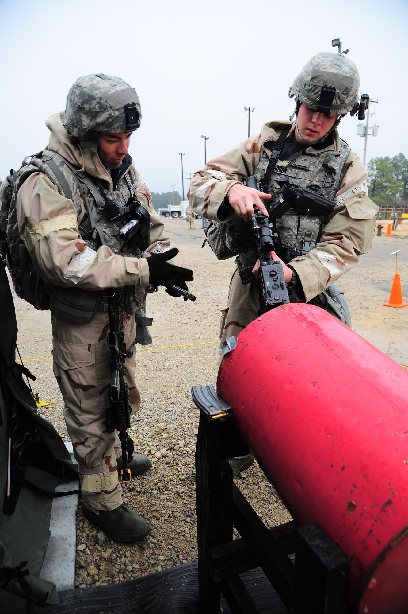 U.S. Air Force Airman 1st Class Willie Gibson, 4th Security Forces Squadron patrolman, clears a weapon as Senior Airman Joseph Ornelas, 4th SFS patrolman, inspects his procedures during Operational Readiness Exercise Coronet Warrior 13-02, at a simulated deployed location on Seymour Johnson Air Force Base, N.C., Feb. 13, 2013. Gibson cleared the weapon for his teammate who was injured during mock small arms fire attack. (U.S. Air Force photo/Airman 1st Class Aubrey White/Released)