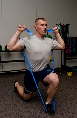 Staff Sgt. Donald Collins, 7th Munitions Squadron, performs the first step of the Resistance band lunge with overhead press exercise. (U.S. Air Force photo by Airman 1st Class Peter Thompson/ Released)