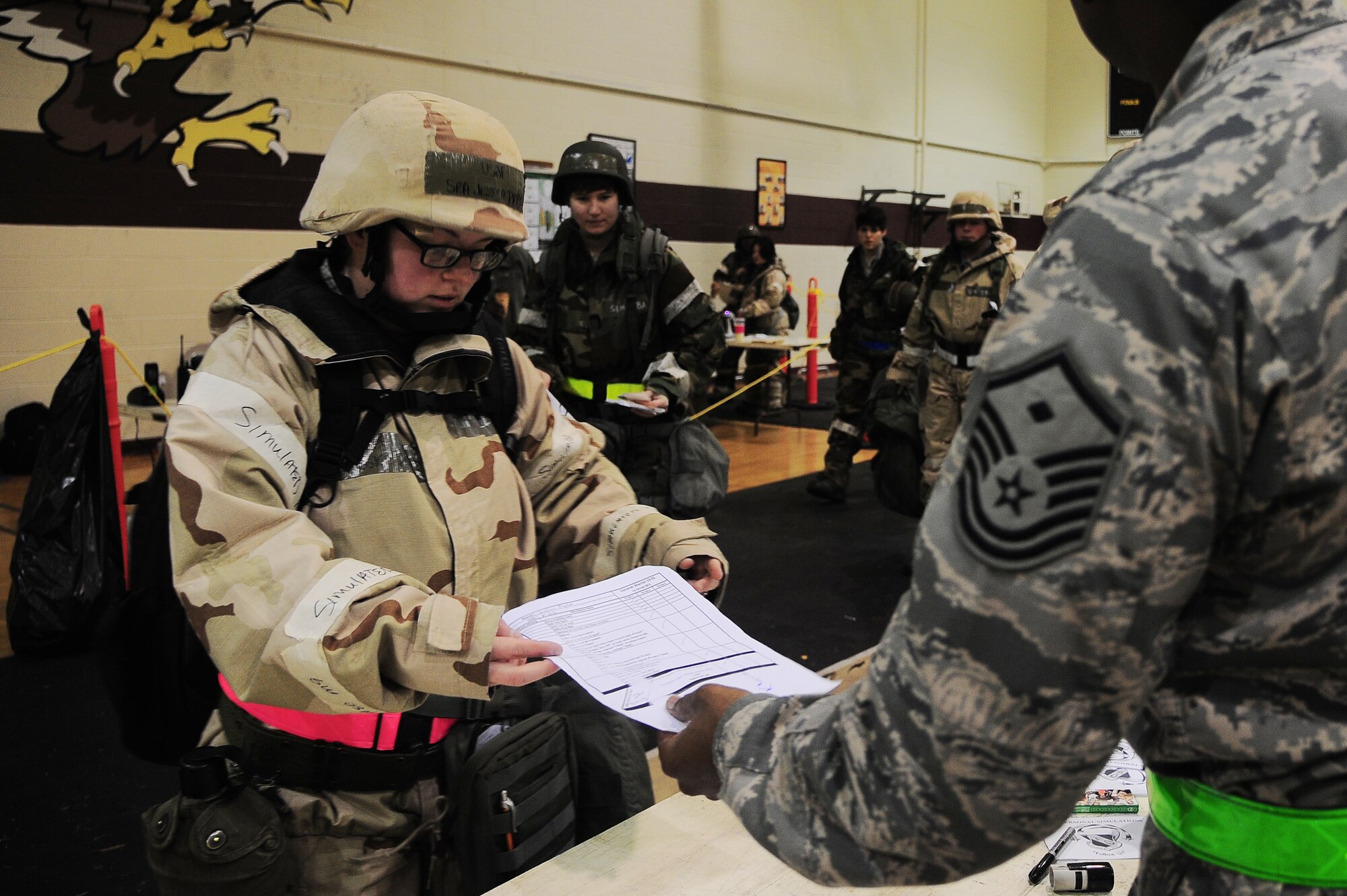 U.S. Air Force Senior Airman Jessica Papke, 4th Operations Support Squadron intelligence analyst, hands her checklist to Master Sgt. Robert Elliott, 4th Force Support Squadron First Sergeant, as she processes through the transition area on Seymour  Johnson Air Force Base, N.C., Feb. 14, 2013. The checklist outlines items which deployed personnel must carry at all times during the Operational Readiness Exercise. (U.S. Air Force photo/Airman 1st Class Aubrey White/Released)