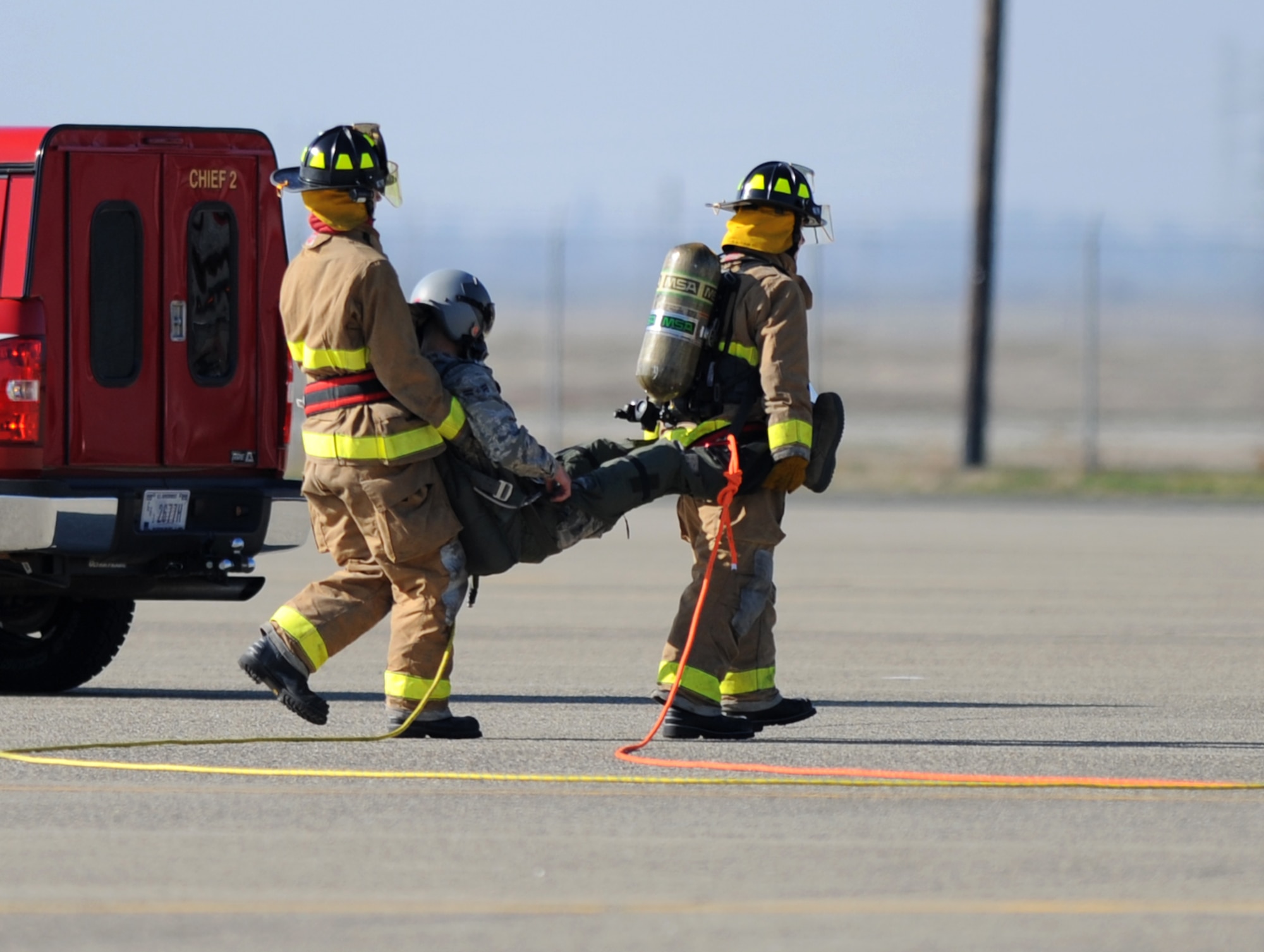 Beale firefighters carry Airman 1st Class Eric Whaley, 9th Civil Engineer Squadron firefighter, to safety during a pilot rescue exercise on the flight-line at Beale Air Force Base, Calif., Feb. 13, 2013. Whaley had the opportunity to portray a pilot of a T-38 Talon jet trainer during the exercise. (U.S. Air Force photo by Staff Sgt. Robert M. Trujillo/Released)