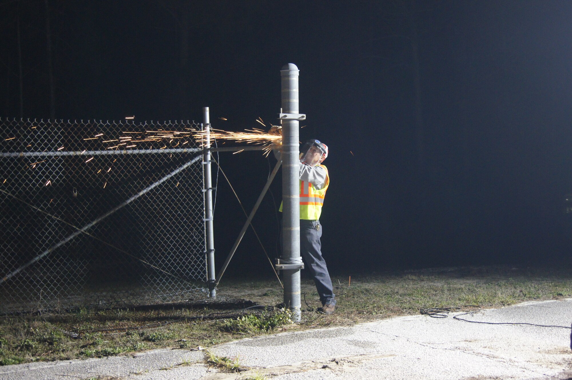 A  contractor works to temporarily alter a gate post to enable the F-15C Eagle to pass through on its way from the flight line side to the support side of the base. (Photo by BJ Marshall)