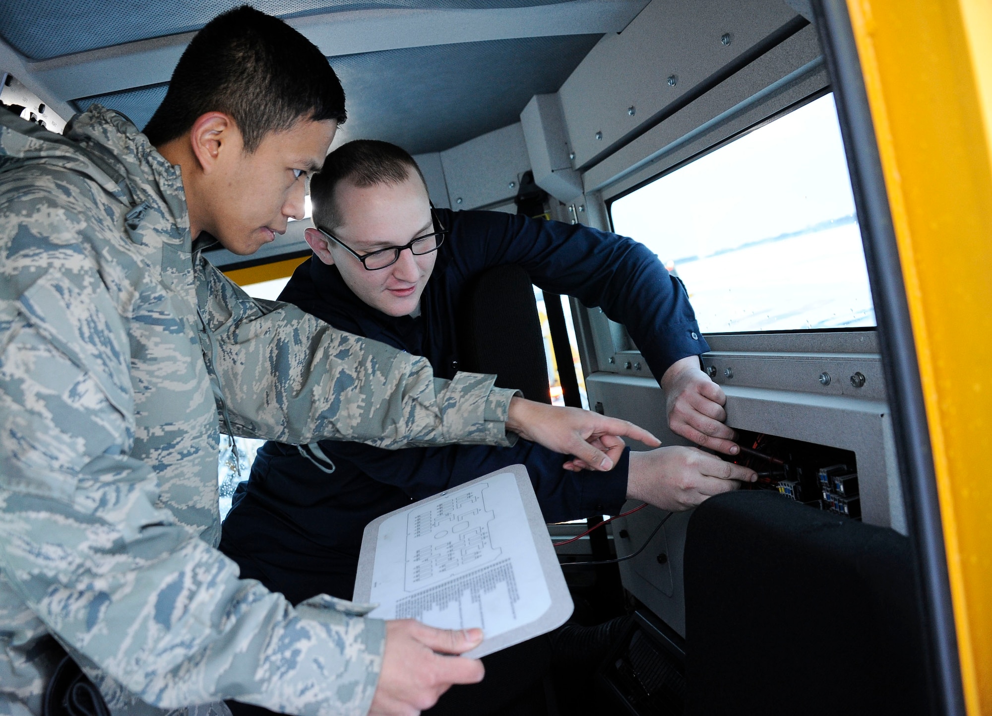 Senior Airman Hiro Dela Cruz and Staff Sgt. Aaron Waldor, 87th Logistics Readiness Squadron vehicle mechanics, replace a bad fuse on a snow plow Feb. 9, 2013, on McGuire Field at Joint Base McGuire-Dix-Lakehurst, N.J. The 87th Civil Engineer Squadron Snow Control team uses an array of equipment, including plows and blowers, all of which 87th LRS vehicle mechanics must keep mission ready. Dela Cruz is from Tobyhanna, Pa., and Waldor hails from Ford City, Pa. (U.S. Air Force photo by Airman 1st Class Ryan Throneberry/Released)