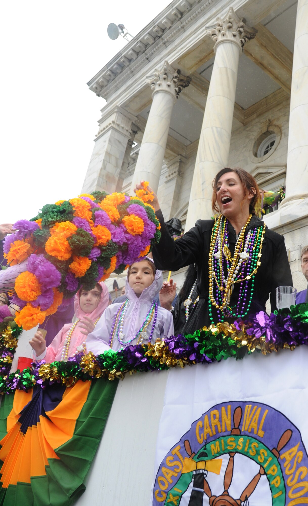 Lisa Spacy, spouse of Brig. Gen. Brad Spacy, 81st Training Wing commander, receives a paper flower as she enjoys the Gulf Coast Carnival Association Mardi Gras parade with the general from city hall in Biloxi, Miss., Feb. 12, 2013.  Col. Craig LaFave, 403rd Wing commander, and the Keesler Honor Guard also participated in the festivities.  (U.S. Air Force photo by Kemberly Groue)