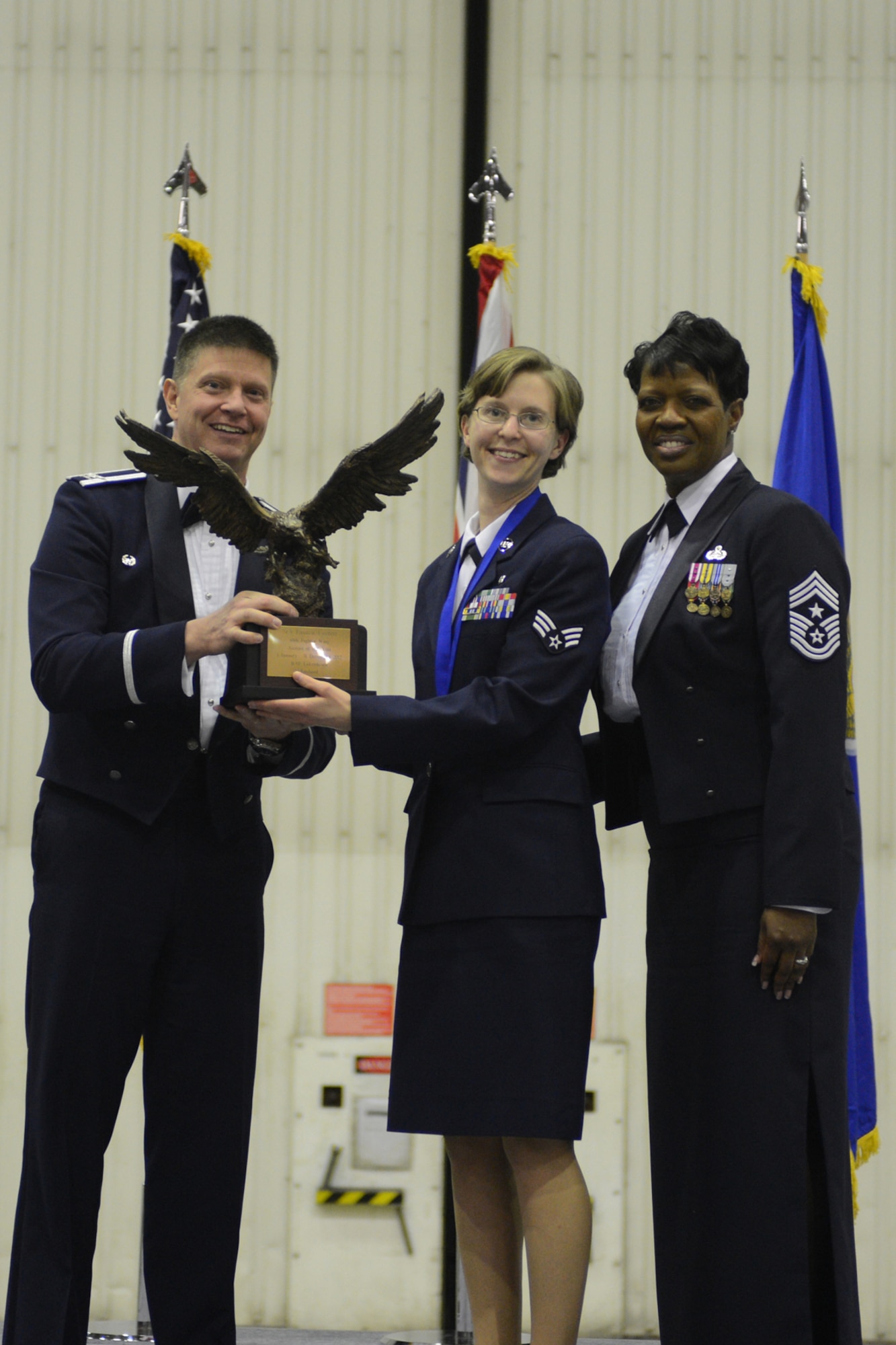 ROYAL AIR FORCE LAKENHEATH, England -- Col. Kyle Robinson, 48th Fighter Wing commander and Chief Master Sgt. SaRita Lathan, 48th FW command chief, present Senior Airman Lauren Everett, 48th Inpatient Squadron medical technician, with the Airman of the Year Award during the 48th FW Annual Awards Banquet at Hangar 7 Feb. 9, 2013. (U.S. Air Force photo by Airman 1st Class Dana J. Butler) 