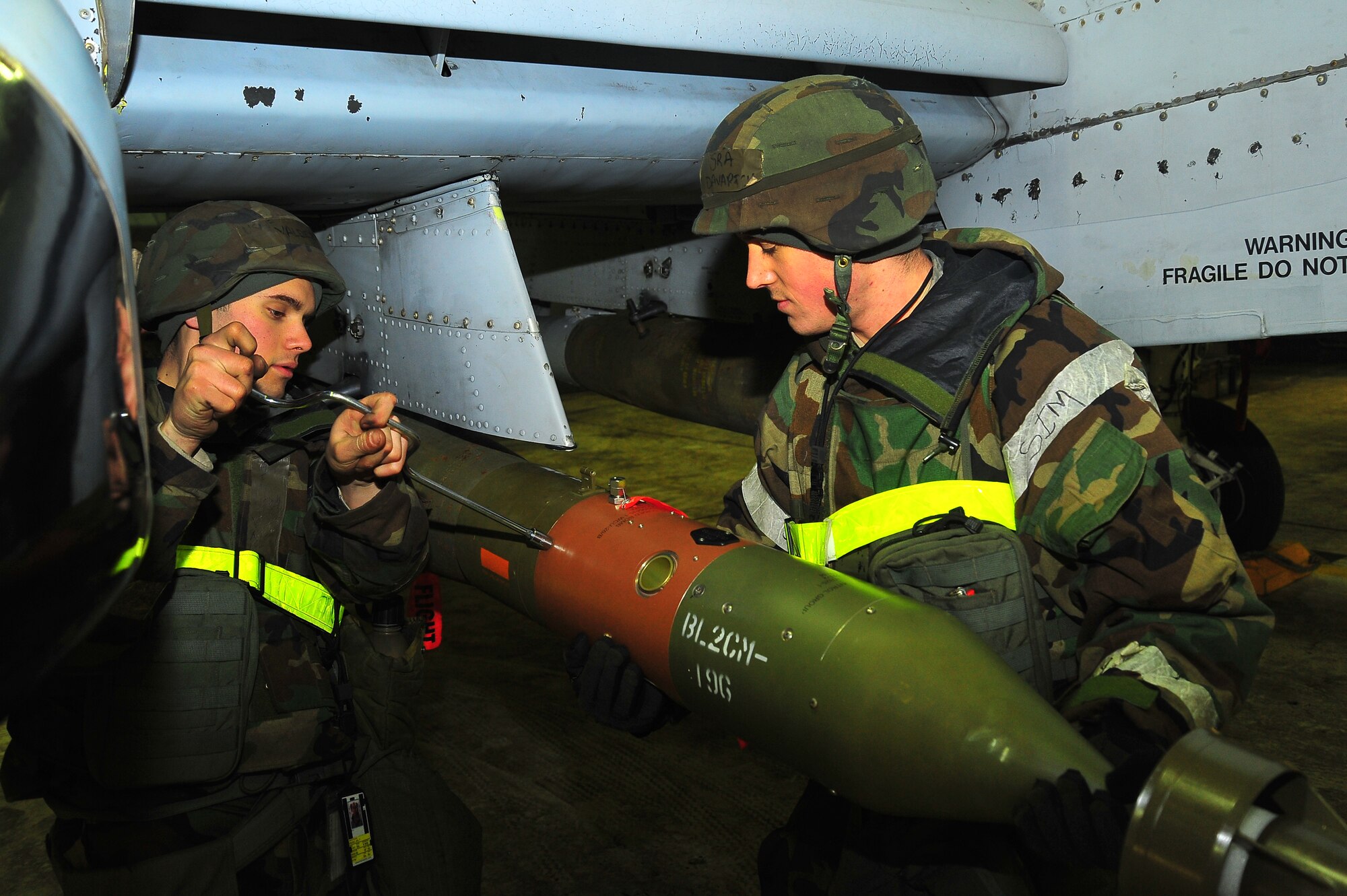 Senior Airman Joel Valdez, left, 51st Maintenance Operation Squadron lead crew member, and Senior Airman Steven Davarich, 51st Maintenance Operation Squadron lead crew member, secure a missile onto an A-10 Thunderbolt II at the flight line on Osan Air Base, Republic of Korea, Feb.13, 2013.  Throughout the week, Osan Mustangs will demonstrate their ability to operate in a chemical environment ensuring the mission can be completed under any conditions.  (U.S. Air Force photo/Staff Sgt. Emerson Nuñez)