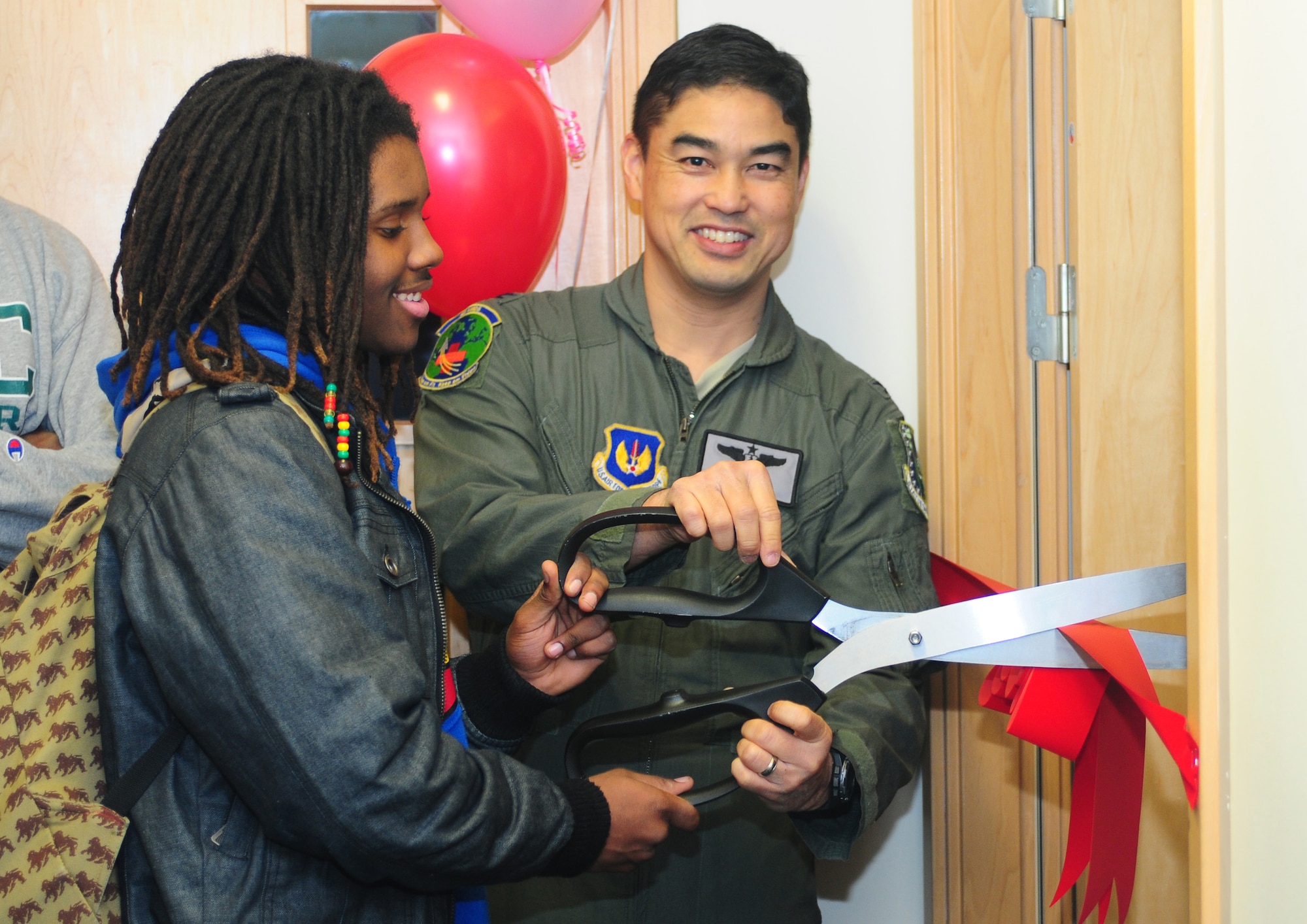 ROYAL AIR FORCE LAKENHEATH, England -- Col. Erik Koda, 48th Aerospace Medicine Squadron commander, and Justin Doze, son of Lt. Col. Elizabeth Anderson-Doze, 48th Aerospace Medicine flight commander, cut a ribbon during a ceremony for the newly refurbished light therapy and relaxation rooms at the RAF Lakenheath Health and Wellness Center Feb. 7, 2013. Anderson-Doze and her son, Justin, painted a Jamaican beach scene in the light therapy room and a Japanese bamboo forest in the relaxation room. (U.S. Air Force photo by Airman 1st Class Dana J. Butler) 