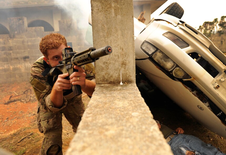 U.S. Air Force Staff Sgt. Manuel Quinonesfigueroa, 31st Rescue Squadron Readiness Flight NCO in charge, takes cover behind a simulated flipped vehicle and provides security during a war week exercise at Marine Corps Camp Hansen's Combat Town, Japan, Feb. 7, 2013. War week, a three-day pre-deployment exercise, gave members from both of Kadena Air Base's rescue squadrons the opportunity to practice numerous rescue scenarios in a controlled environment. (U.S. Air Force photo/Senior Airman Maeson L. Elleman)