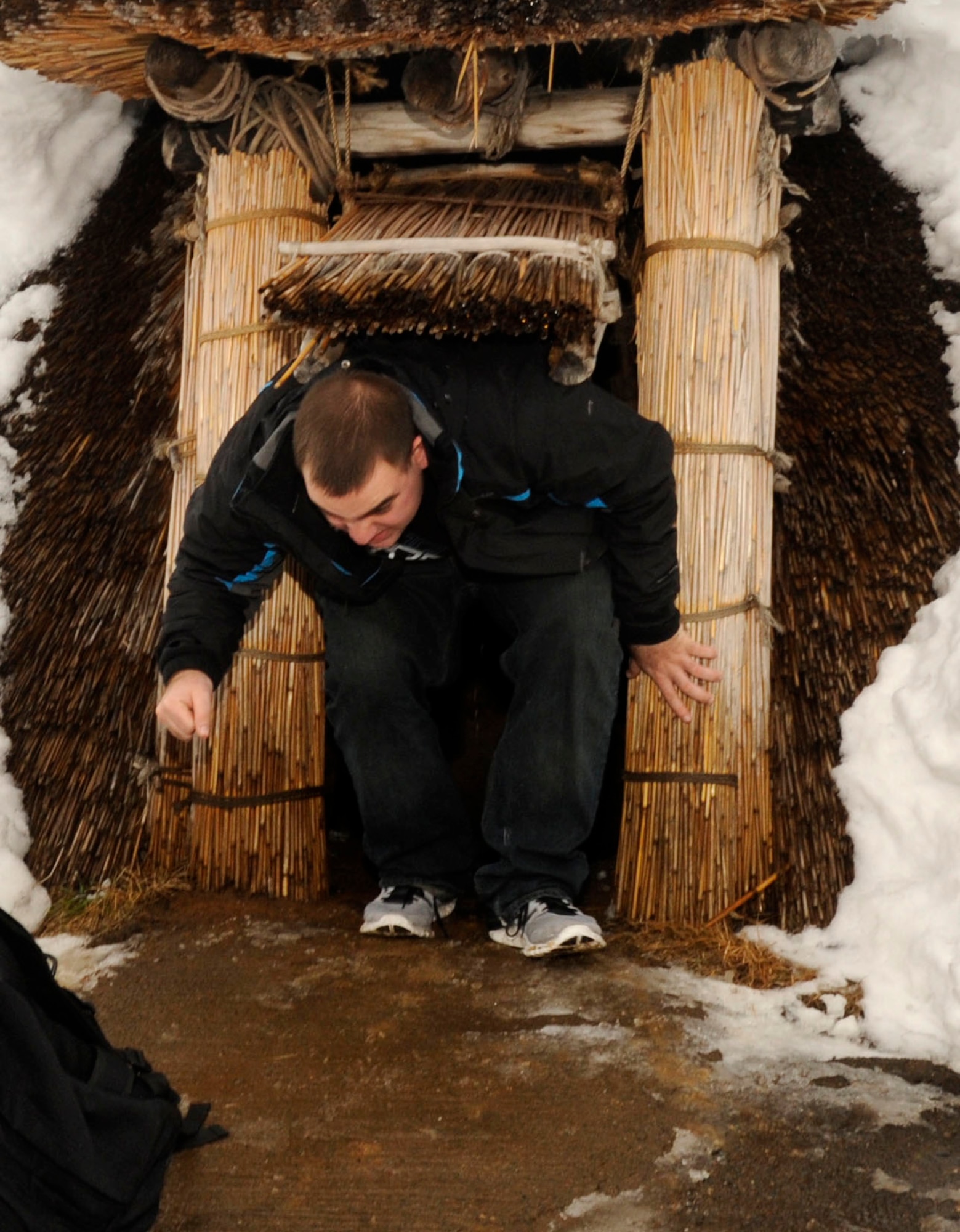 U.S. Air Force Airman 1st Class Christopher Maire, 610th Air Control Flight unit deployment manager, climbs out of a reconstructed pit-dwelling at the Sannai-Maruyama site in Aomori, Japan, Feb. 2, 2013. Pit-dwellings, semi-subterranean structures with circular of oval floor plans, were the most common type of residential buildings during the Jomon period. (U.S. Air Force photo by Airman 1st Class Kenna Jackson)