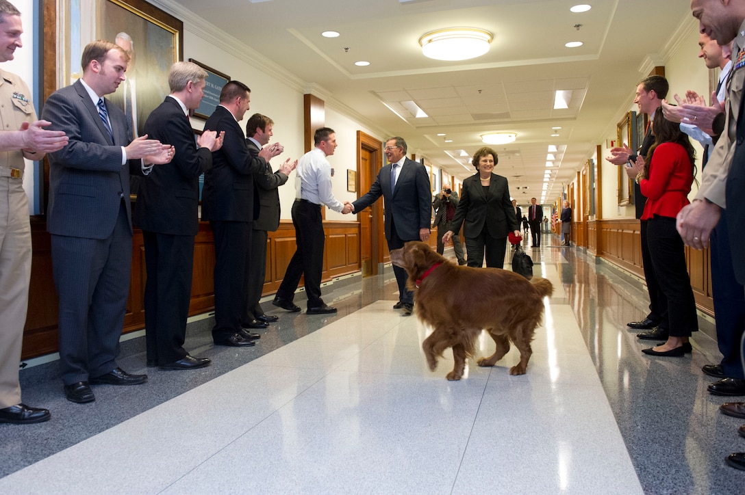 Defense Secretary Leon E. Panetta, his wife, Sylvia, and their dog, Bravo, walk through crowds of cheering Defense Department workers and military members, Feb. 14, 2013. Panetta will remain secretary of defense until his successor is confirmed and sworn in.