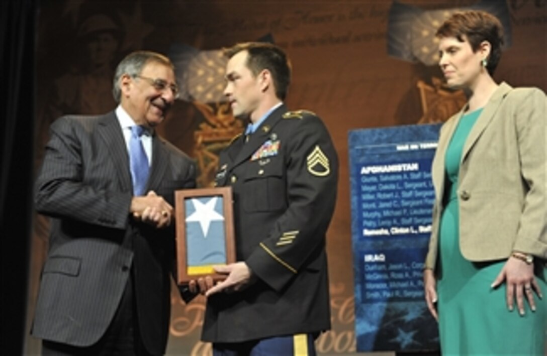 Secretary of Defense Leon E. Panetta presents former Army Staff Sgt. Clinton L. Romesha with a Medal of Honor Flag while his wife Tammy looks on during a ceremony in the Pentagon on Feb. 12, 2013.  President Barak Obama presented the Medal of Honor to Romesha in a ceremony yesterday at the White House.  Romesha earned the medal for actions on Oct. 3, 2009, at Combat Outpost Keating in Afghanistan.  