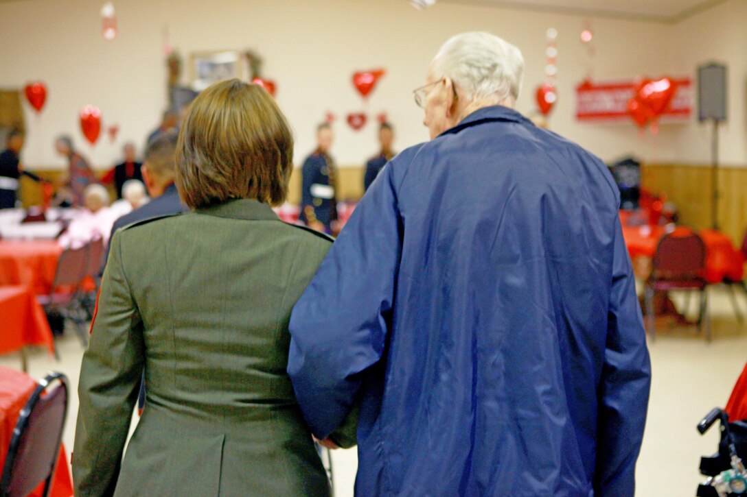 Sgt. Rachael K. A. Moore (left), a volunteer with 2nd Marine Logistics Group, escorts a resident of Carebridge Assisted Living center in Jacksonville, N.C., Feb. 12, 2013. The facility hosted a Sweetheart Dance and invited Marines from various units to dance, sing, eat and socialize with the residents. 