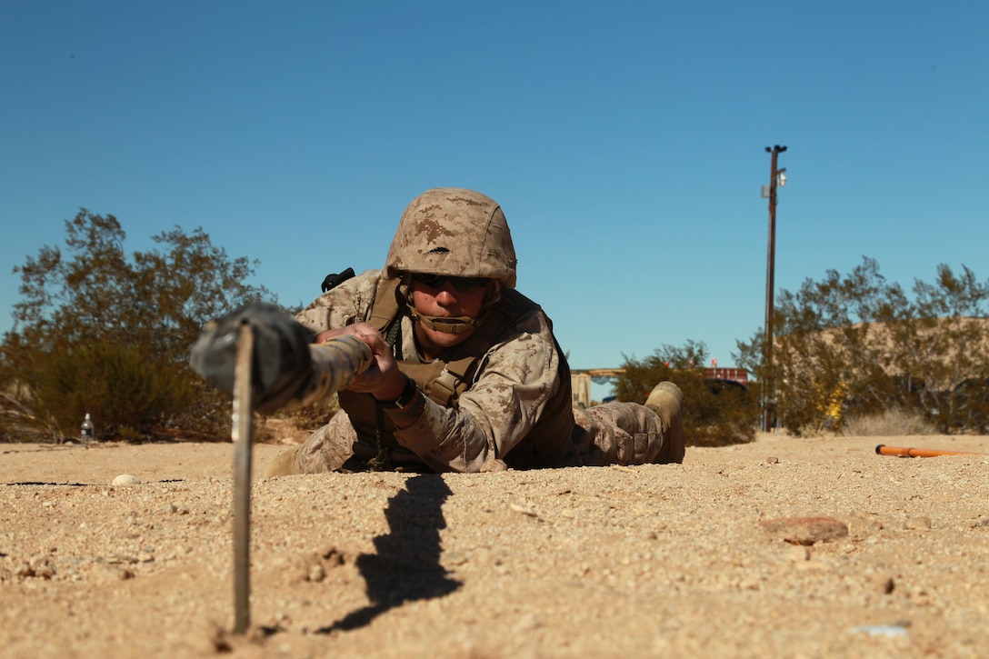 Seaman Chatwinderjit Nagra, hospital corpsman, 3rd Combat Engineer Battalion, employs a bamboo sickle stick to search for buried improvised explosive devices at the Combat Center's Range 800 Feb. 13, 2013.