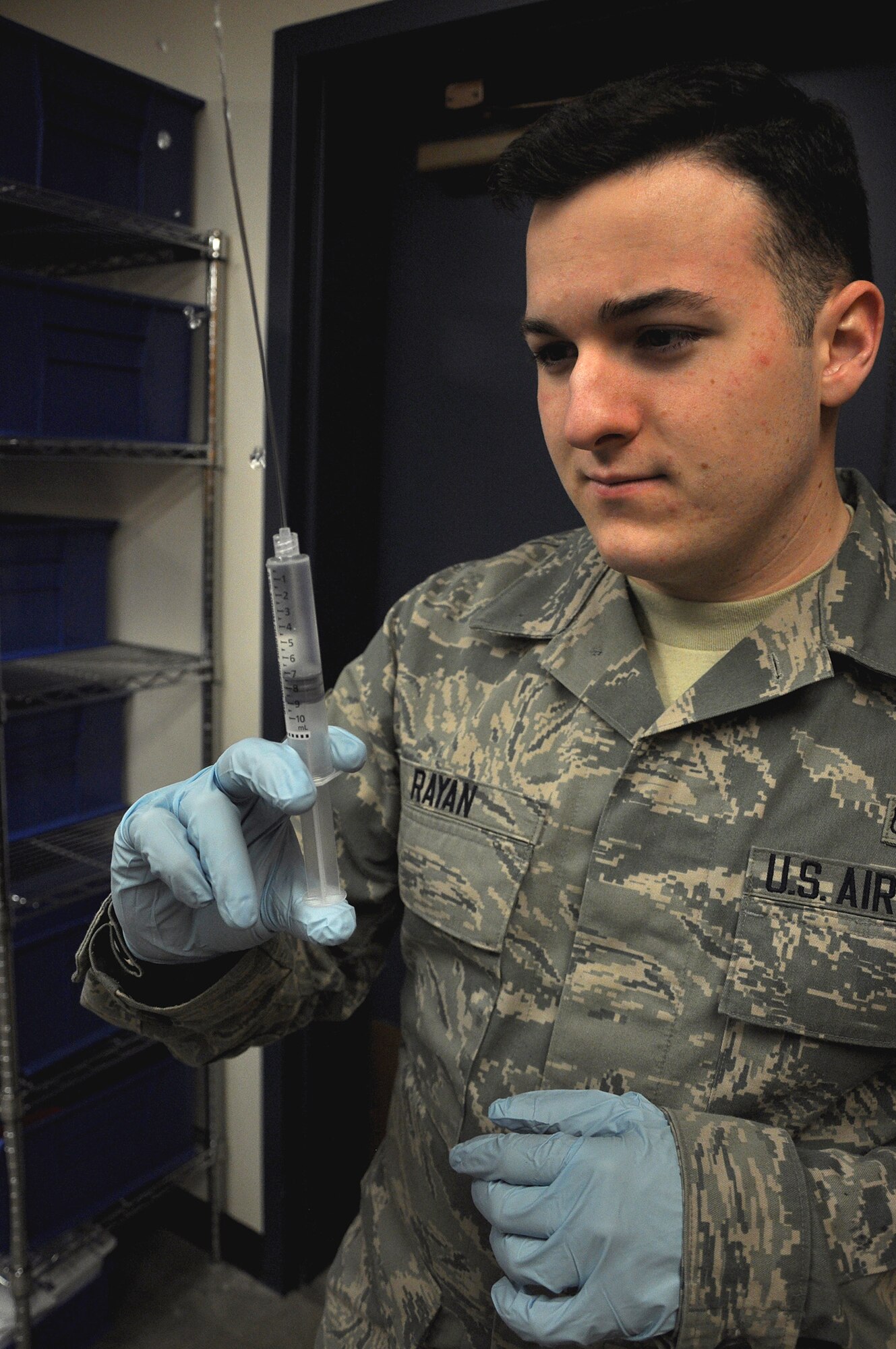 Airman 1st Class Barrett Rayan, 446th Aeromedical Evacuation Squadron, pushes the air out of a saline flush Feb. 14 at the 446th AES. Rayan is nearly half-way through his medical technician training and recently helped save his first life by performing CPR on a baby when it went into cardiac arrest. (U.S. Air Force Photo/Airman 1st Class Madelyn McCullough)