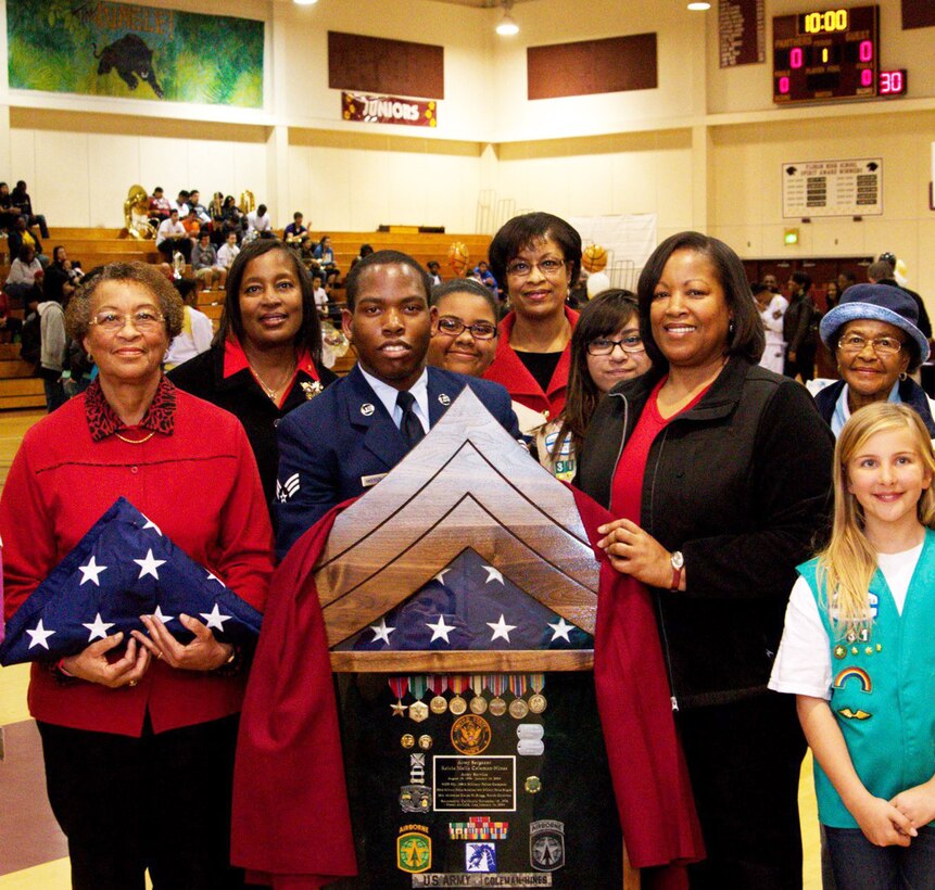 TRAVIS AIR FORCE BASE, Calif. -- Pictured here are Senior Amn. Bryan Anderson-Wooten, 60th Civil Engineer Squadron, and Beverly Coleman, the  mother of Sergeant Keicia Coleman-Hines, Class of 1994, who was killed Jan. 14, 2004, while deployed to Mosul Airfield, Iraq, holding a shadow box presented to her. On the left is Mary Coleman, grandmother of Coleman-Hines, holding a folded flag that flew over the U.S. Capitol Jan. 14, 2013, the ninth anniversary of the sergeant's passing. Next to Beverly Coleman, in the blue hat, is her grandmother, Ida Wheeler. Another sister is at the back, and the group is surrounded by the Girl Scouts of Troop 1756.  (Courtesy photo)