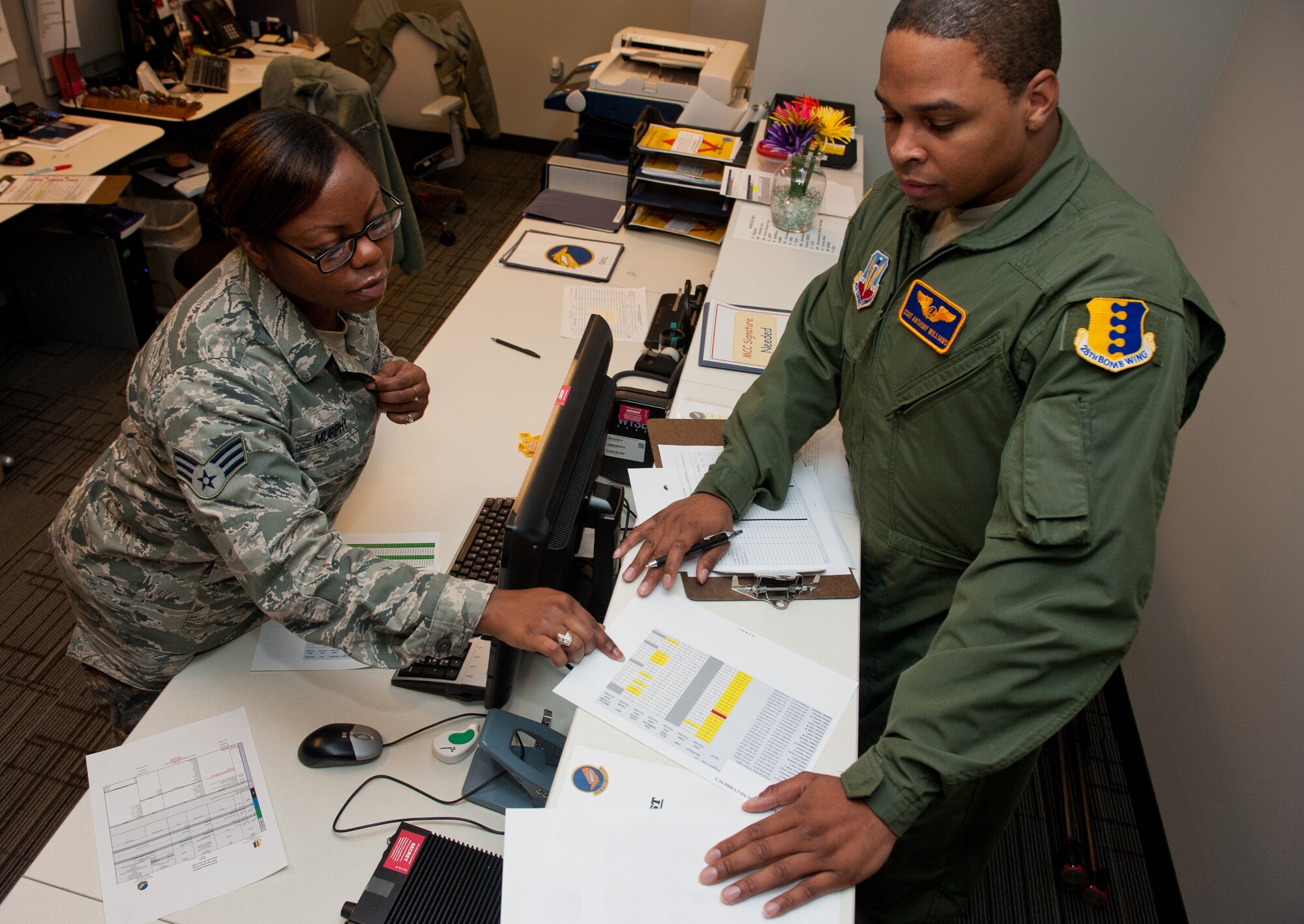 Senior Airman Alexandria Murphy, 432nd Attack Squadron aviation resource manager, reviews a flight record with Staff Sgt. Anthony Williams, 432nd ATKS sensor operator, in the SARM office on Ellsworth Air Force Base, S.D., Jan. 28, 2013. SARM Airmen create itineraries and track qualifications, training and flight records for aircrews at Ellsworth. (U.S. Air Force photo by Airman 1st Class Kate Thornton-Maurer/Released)