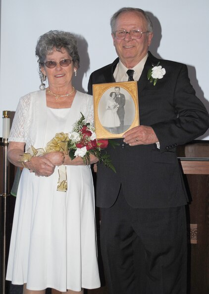 Jacque and Dennis Ellingson pose with a photo of them on their wedding day 50 years ago following their vow renewal ceremony Feb. 8.  Dennis was able to surprise Jacque by bringing her to the exact spot they were married to renew their vows.  (U.S. Air Force photo/Senior Airman Cortney Paxton)