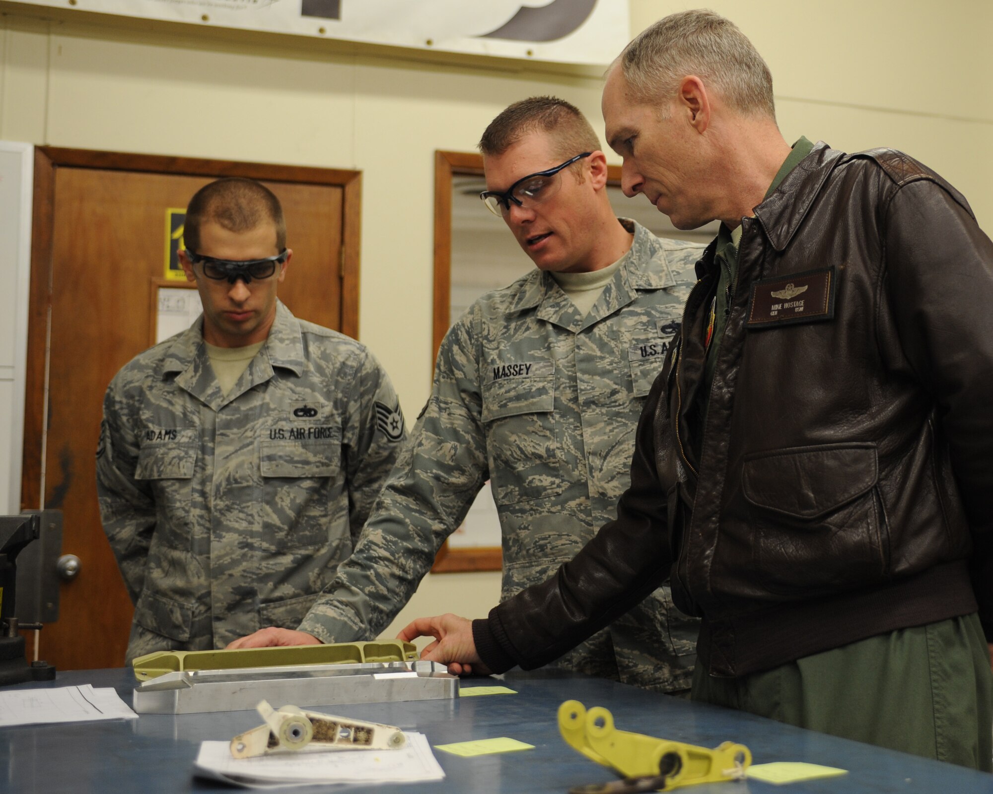 U.S. Air Force Staff Sgt. Denson Adams, left, and Tech. Sgt. Christopher Massey, center, 7th Equipment Maintenance Squadron, explain how various aircraft parts are manufactured to Gen. Mike Hostage, commander of Air Combat Command, Feb. 12, 2013, at Dyess Air Force Base, Texas. During his visit, Hostage had the opportunity to see how the metals technology flight manufactures highly precise aircraft parts out of aluminum. (U.S. Air Force photo by Staff Sgt. Richard P. Ebensberger/Released)