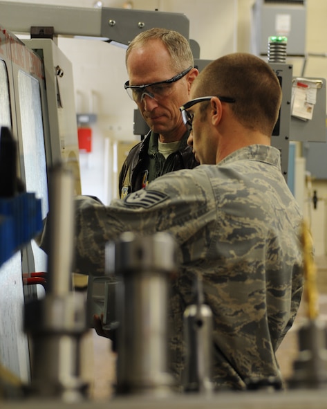 U.S. Air Force Gen. Mike Hostage, commander of Air Combat Command, is shown how to use a computer numerical control milling machine by Staff Sgt. Denson Adams, 7th Equipment Maintenance Squadron, Feb. 12, 2013, at Dyess Air Force Base, Texas. During his visit, Hostage had the opportunity to see how the metals technology flight manufactures highly precise aircraft parts out of aluminum. (U.S. Air Force photo by Staff Sgt. Richard P. Ebensberger/Released)