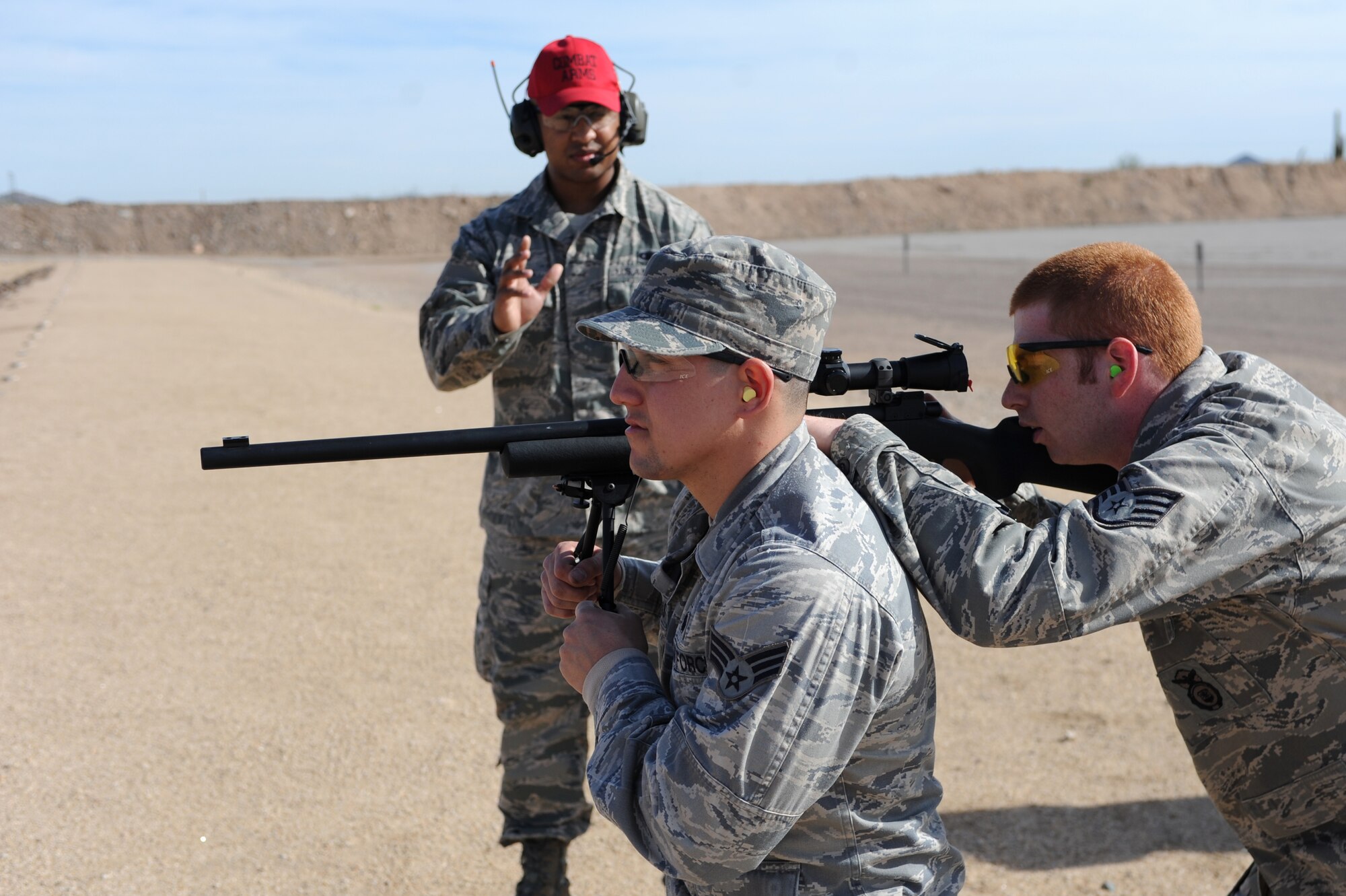 Senior Airman Erik Williams, 56th SFS combat arms training instructor, watches Staff Sgt. Brady Craddock, 56th SFS combat arms training instructor, use Senior Airman Gabriel Cuevas, 56th SFS Bravo Flight, as shooting support during the requalification training at the Ben Avery Shooting Range north of Phoenix. The purpose of requalification is for shooters to maintain their skills as advanced designated marksman snipers. (U.S. Air Force photo/Airman 1st Class Devante Williams)