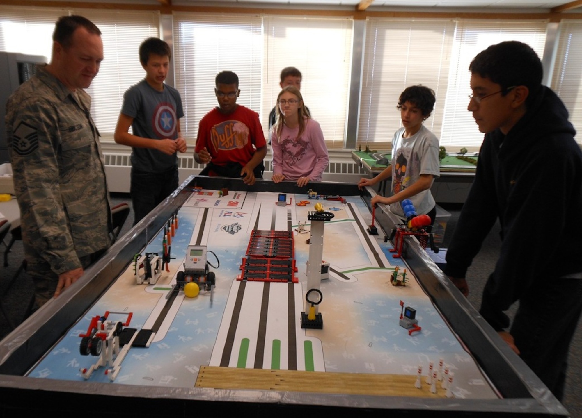 MINOT AIR FORCE BASE, N.D. -- Members of the Ferocious Firebirds and Master Sgt. Clint G. Ericson, 5th Logistics Readiness Squadron fuels superintendent and team coach, work on their entry for the FIRST LEGO League team competition held recently in Grand Forks, N.D. The team of students from Memorial Middle School won first place for Teamwork. Their winning Lego robotics design was an idea to make driving safer for the elderly. (Courtesy photo)