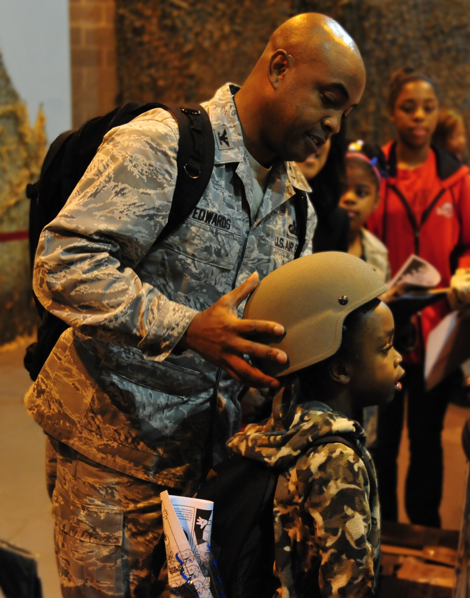 Colonel Trent Edwards, 42nd Air Base Wing Commander, places a helmet on his son Dylan during the inaugural Kids, Spouses and Teachers Understanding Deployment Operations, or KUDOS, SUDOS and TUDOS event, held Saturday on Maxwell. (U.S. Air Force photo by Senior Airman Christopher Stoltz)