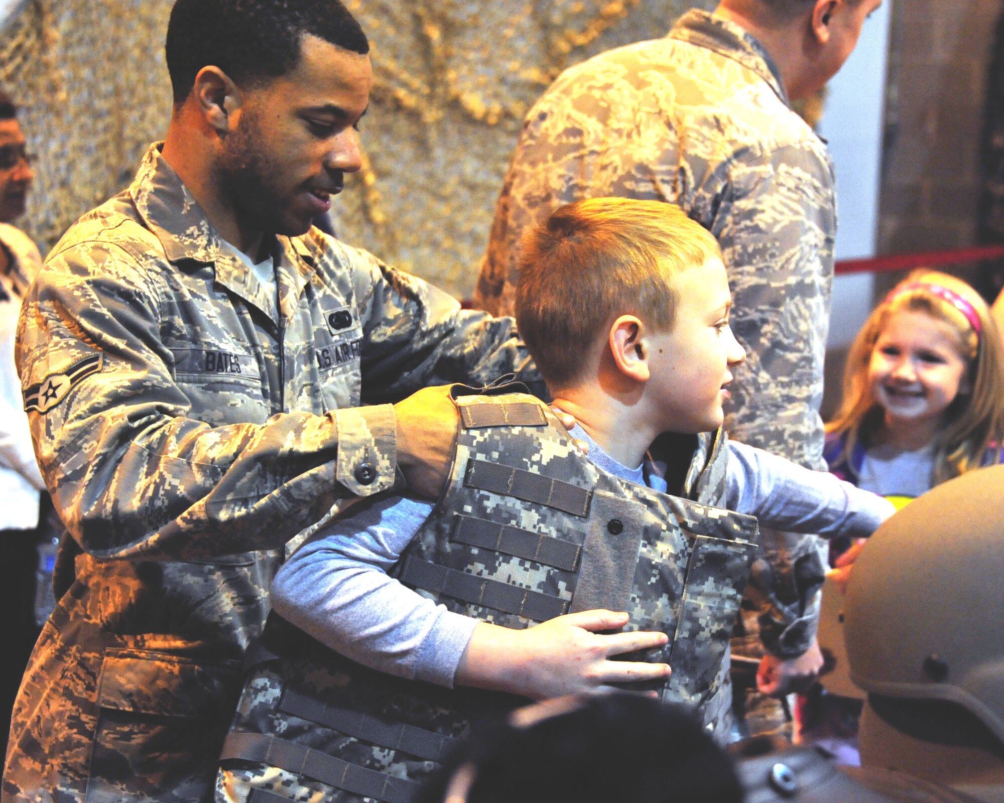 Airman 1st Class Monterrius Bates helps Ethan Dixon try on Kevlar during the deployment line of the inaugural Kids, Spouses and Teachers Understanding Deployment Operations, or KUDOS, SUDOS and TUDOS event, held Saturday on Maxwell. (U.S. Air Force photo by Senior Airman Christopher Stoltz)