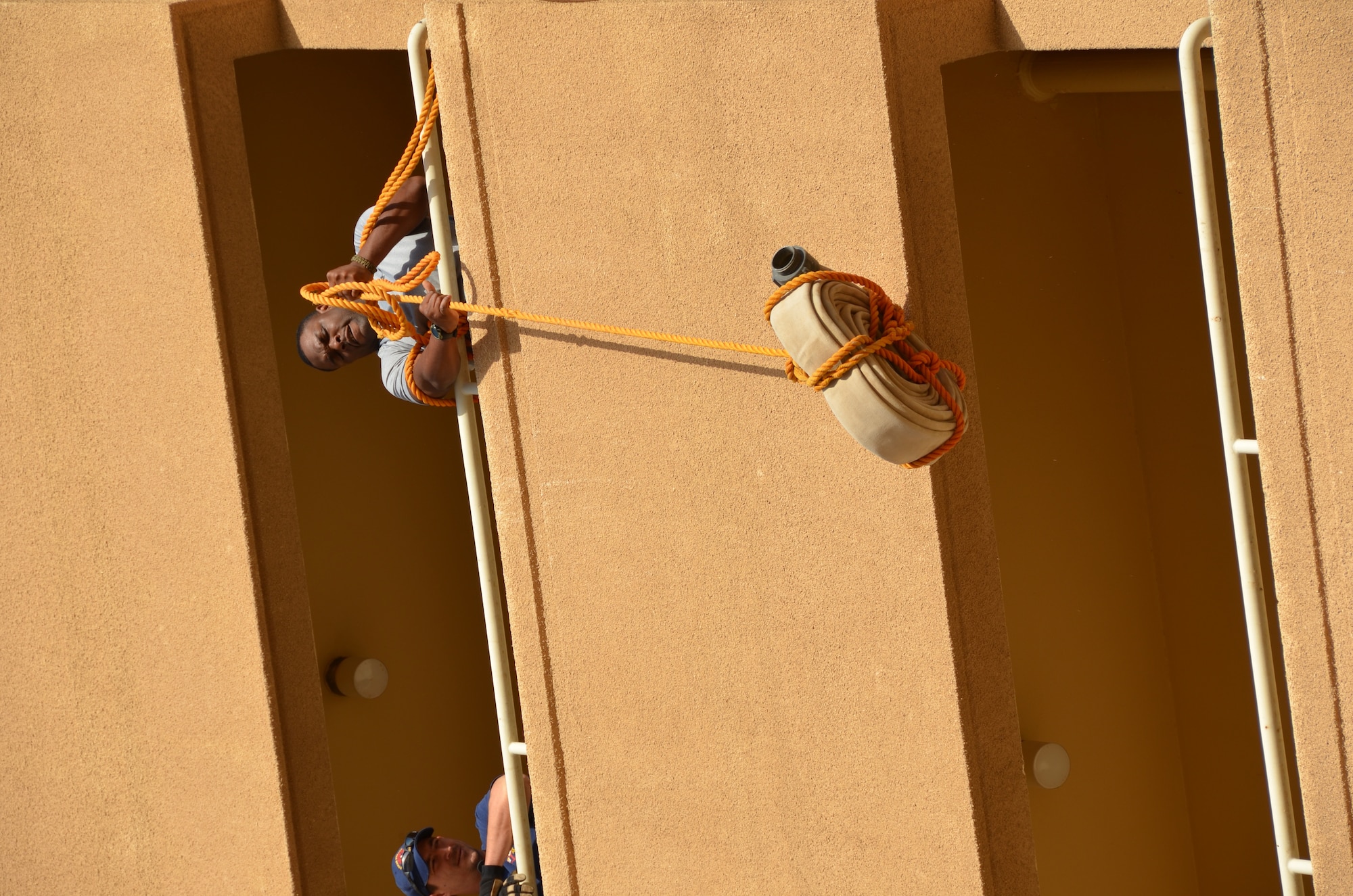 Tech. Sgt. Taravus Melton, 64th Air Expeditionary Group staff, competes in the firefighter’s challenge, Jan. 25, hauling up a 42-pound section of fire hose. Members of the group competed in the annual three-day Commander's Cup in Southwest Asia. Events included M-16A2 assault rifle assembly, carrying sand bags, pushing a HMMWV, a home run derby, firefighter's challenge and others before a final steak cookout.(U.S. Air Force photo/Capt. Justin Nikodem)