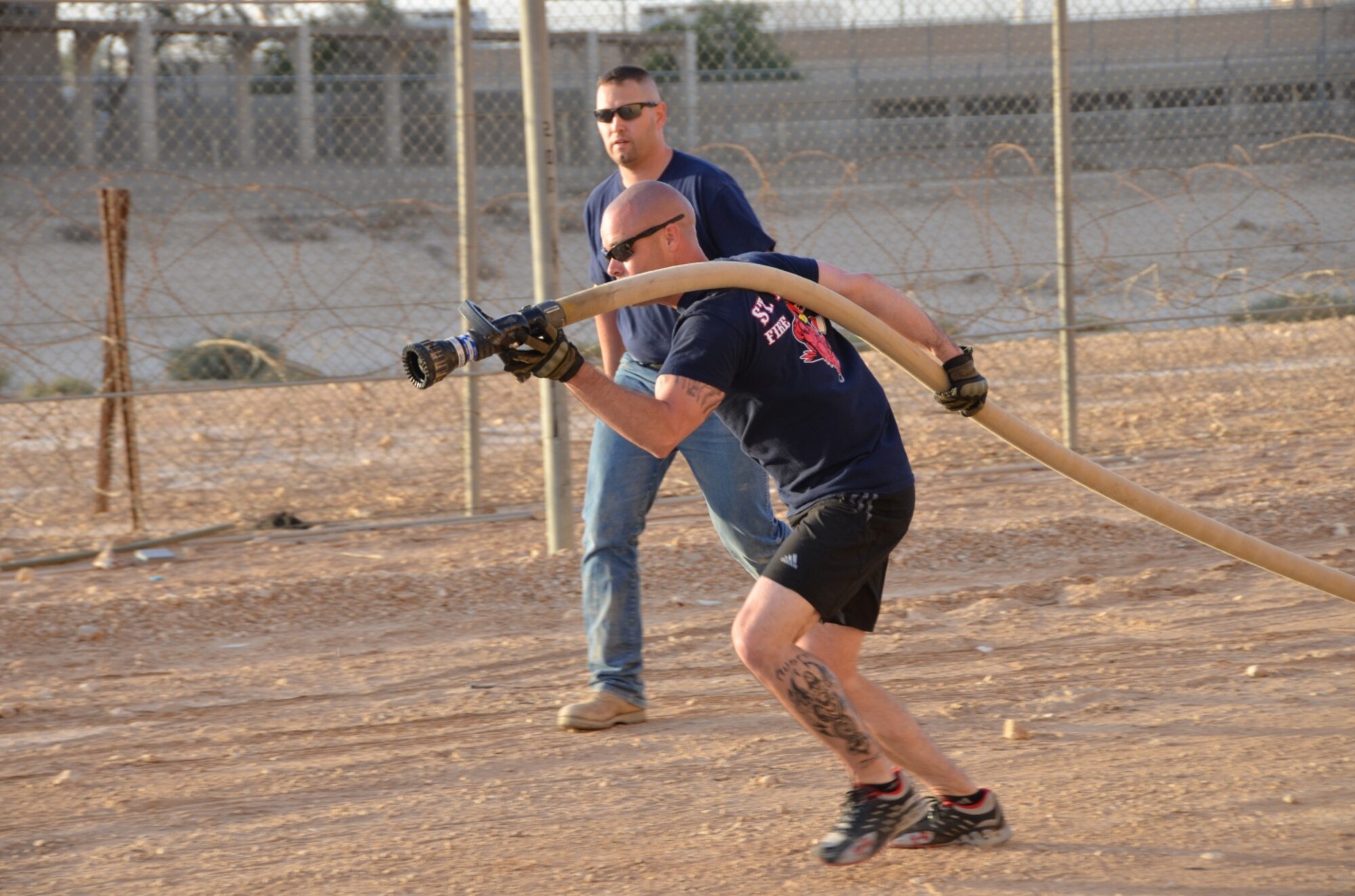 Master Sgt. David Kalal, 64th Expeditionary Security Forces Squadron first sergeant, carries a charged fire hose, Jan. 25, in the firefighter’s challenge. Members of the 64th Air Expeditionary Group competed in the annual three-day Commander's Cup in Southwest Asia. Events included M-16A2 assault rifle assembly, carrying sand bags, pushing a HMMWV, a home run derby, firefighter's challenge and others before a final steak cookout. (U.S. Air Force photo/Capt. Justin Nikodem)