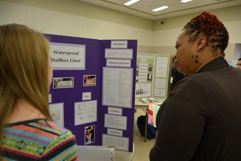 Erica Fox, Middle East District Contracting Division, listens while a student describes her waterproof mailbox liner.