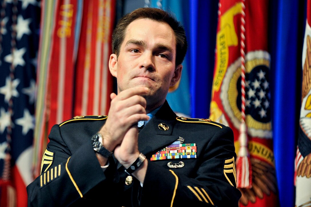 Former Army Staff Sgt. Clinton L. Romesha applauds as he points out surviving members of his unit to stand during a ceremony at the Pentagon, Feb. 12, 2013, recognizing him for receiving the Medal of Honor.