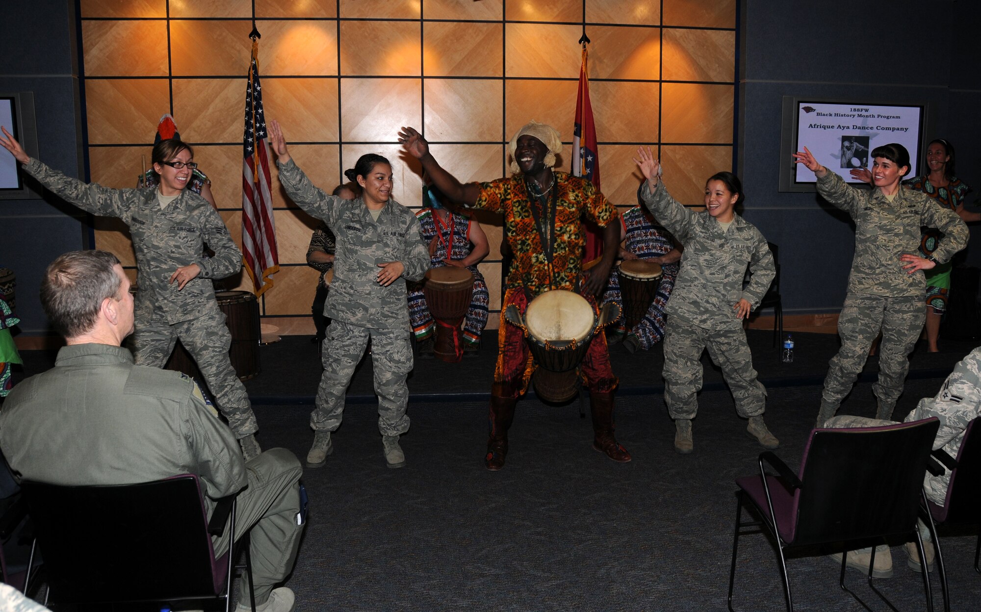 Senior Airman Julie Darrough, left, Senior Airman Hannah Landeros, Staff Sgt. Caressa Soriano and Tech Sgt Michelle Malone dance with a member of Afrique Aya, a troupe of drummers and dancers, during a performance at the 188th Fighter Wing during a Black History Month celebration held at the Hugh B. Correll Headquarters building Feb. 3. The group performed rhythms inspired by the music and culture of West Africa. (National Guard photo by Airman 1st Class Cody Martin/188th Fighter Wing Public Affairs)