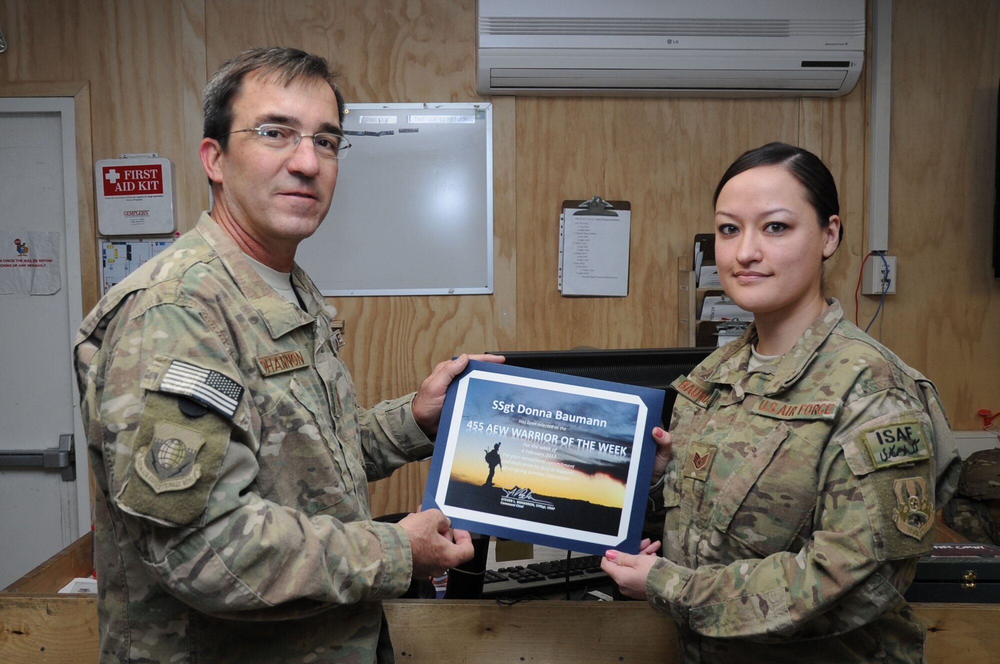 Chief Master Sgt. Steve Bohannon, Command Chief Master Sergeant of the 455th Air Expeditionary Wing, presents the "Warrior of the Week" award to Staff Sgt. Donna Baumann, 455th Expeditionary Aeromedical Evacuation Squadron aviation resource manager, on Bagram Airfield, Afghanistan, Feb. 15, 2013. Baumann is responsible for getting the proper authorizations for patients to travel on flights out of Bagram. (U.S. Air Force photo/Staff Sgt. David Dobrydney)
