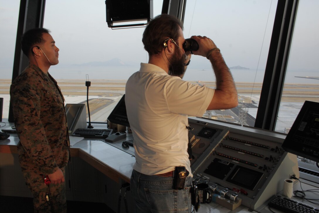 Staff Sgt. Richard Saenz, a Headquarters and Headquarters Squadron air traffic controller, and Bill Banakos, air traffic controller, monitor ongoing operations on the air field as well as waiting for an incoming flight at the air traffic control tower here, Jan. 16, 2013. Saenz supervises other traffic controllers to ensure operations run smoothly. Saenz has been stationed at Marine Corps Air Station Iwakuni since Jan. 9, 2011.
